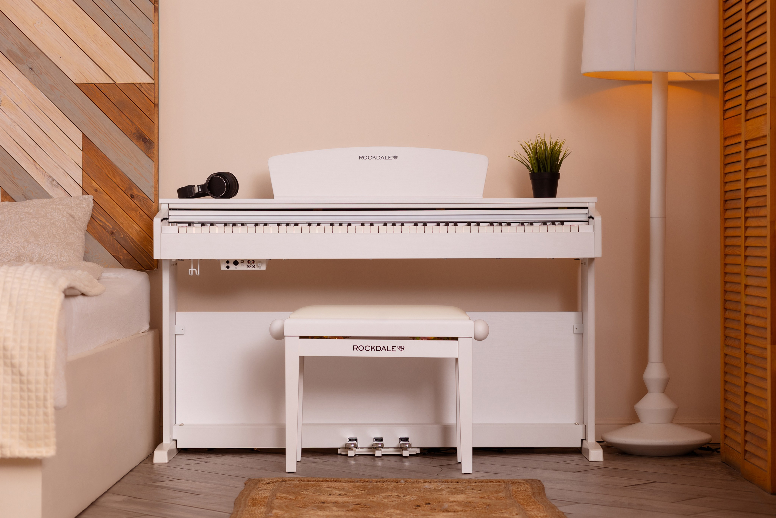 У стены стоит белое фортепиано. На пианино лежит микрофон.