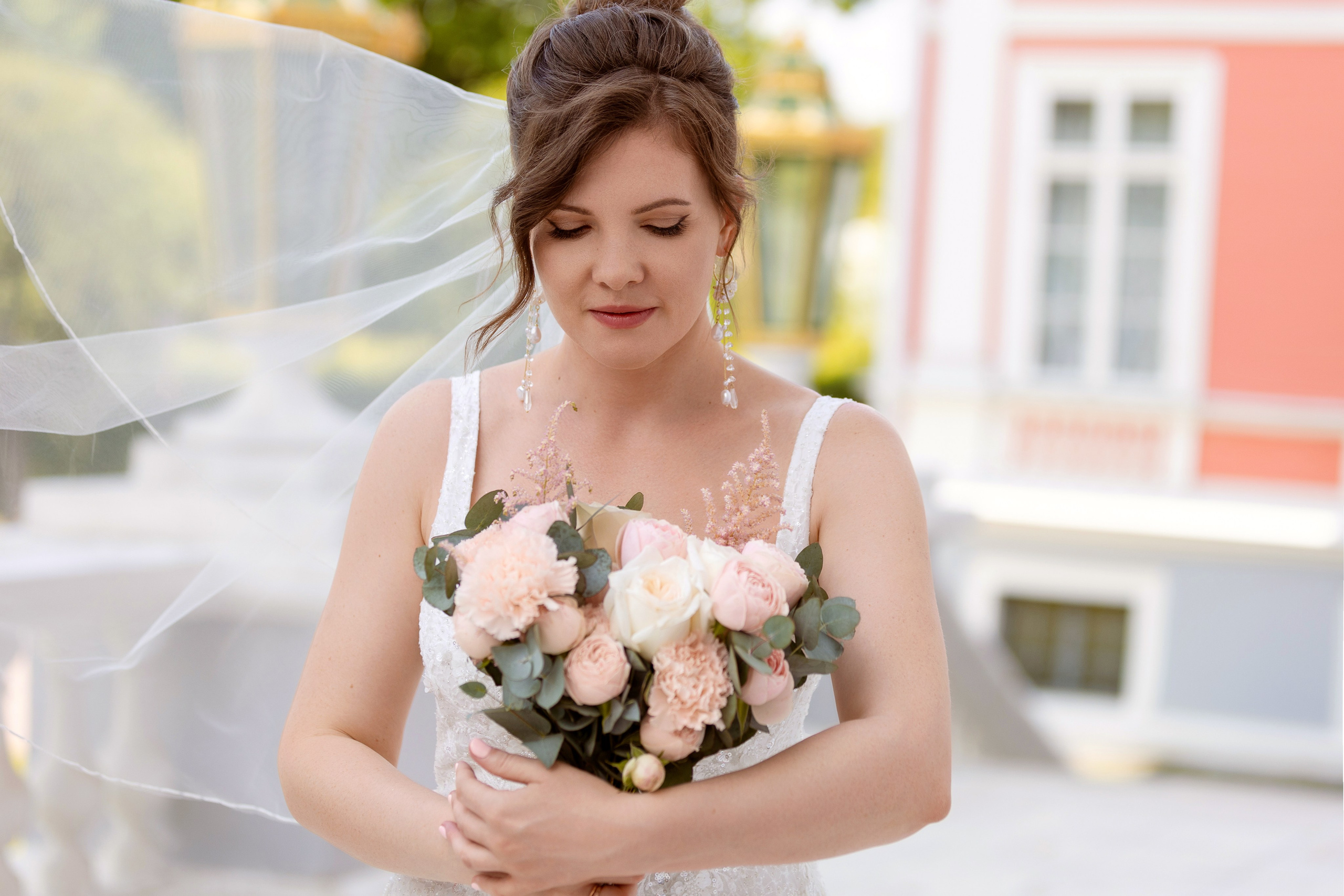 Невеста смотрит на свадебный букет и улыбается
