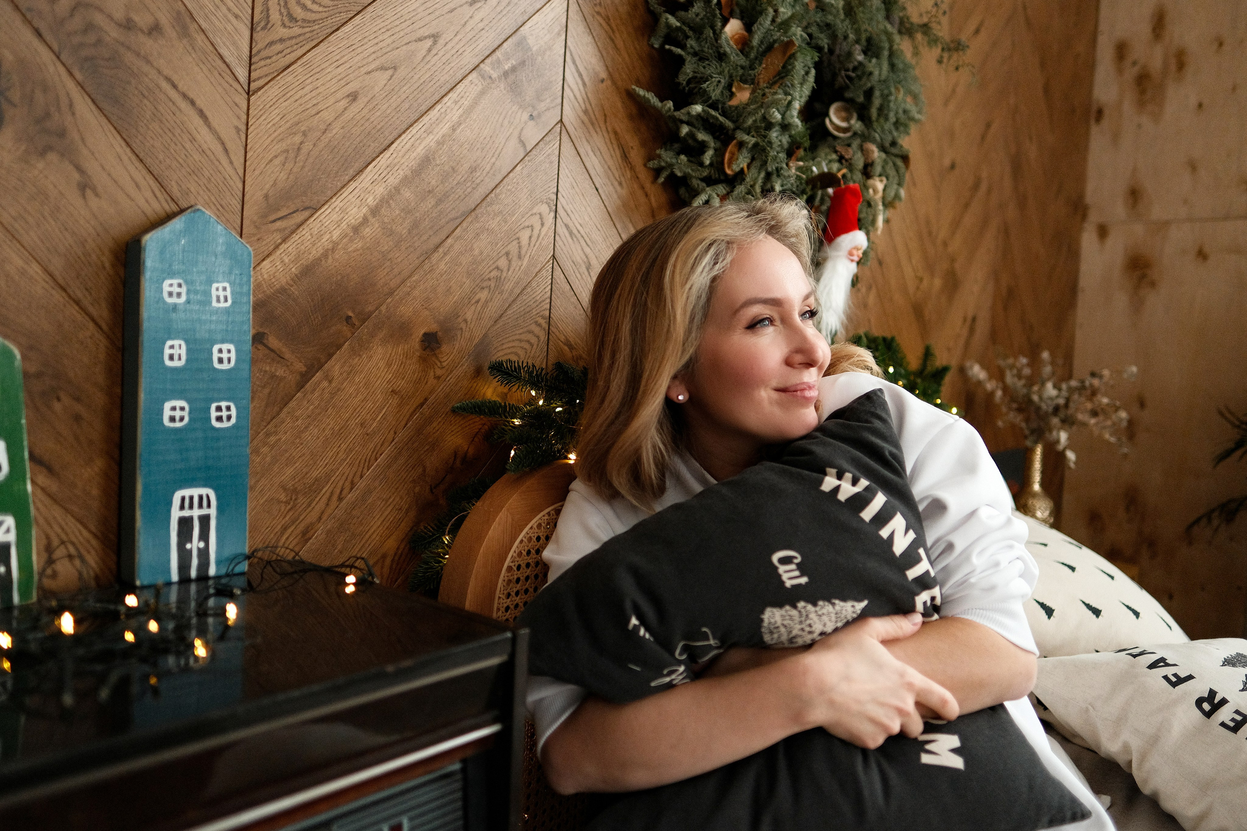 Фотография женщины в светлом пуловере обнимает подушку. Фотосессия в студии, Москва.