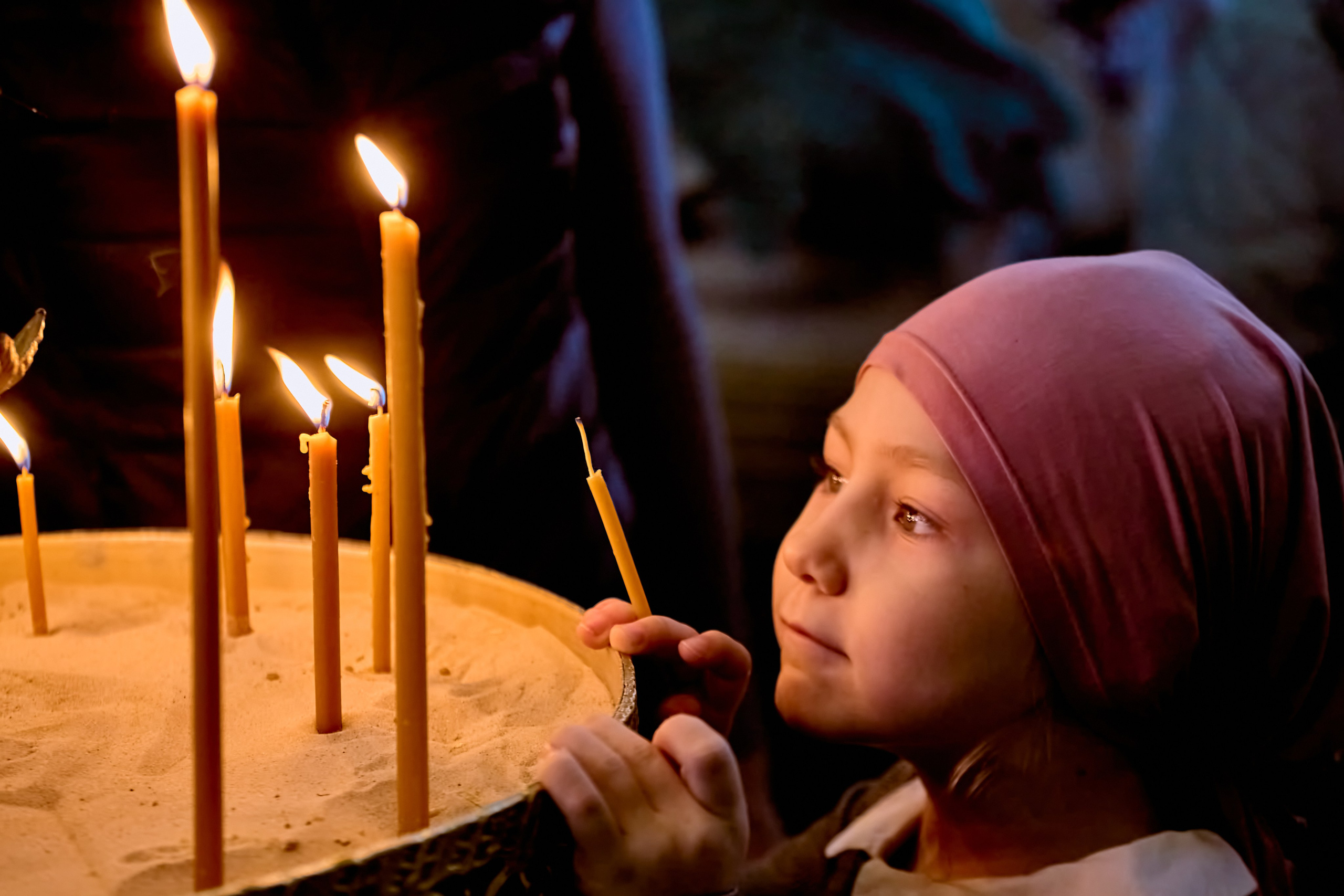 Девочка, 6 лет,  возжигает свечу на праздничном подсвечнике