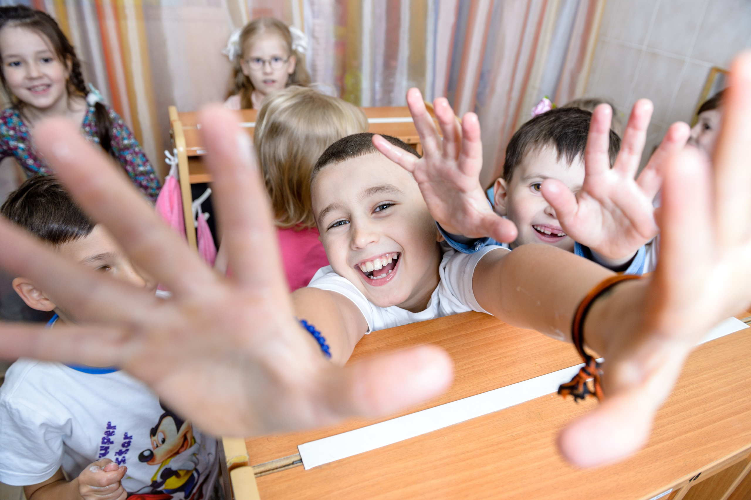 Дети тянут ладони к камере.