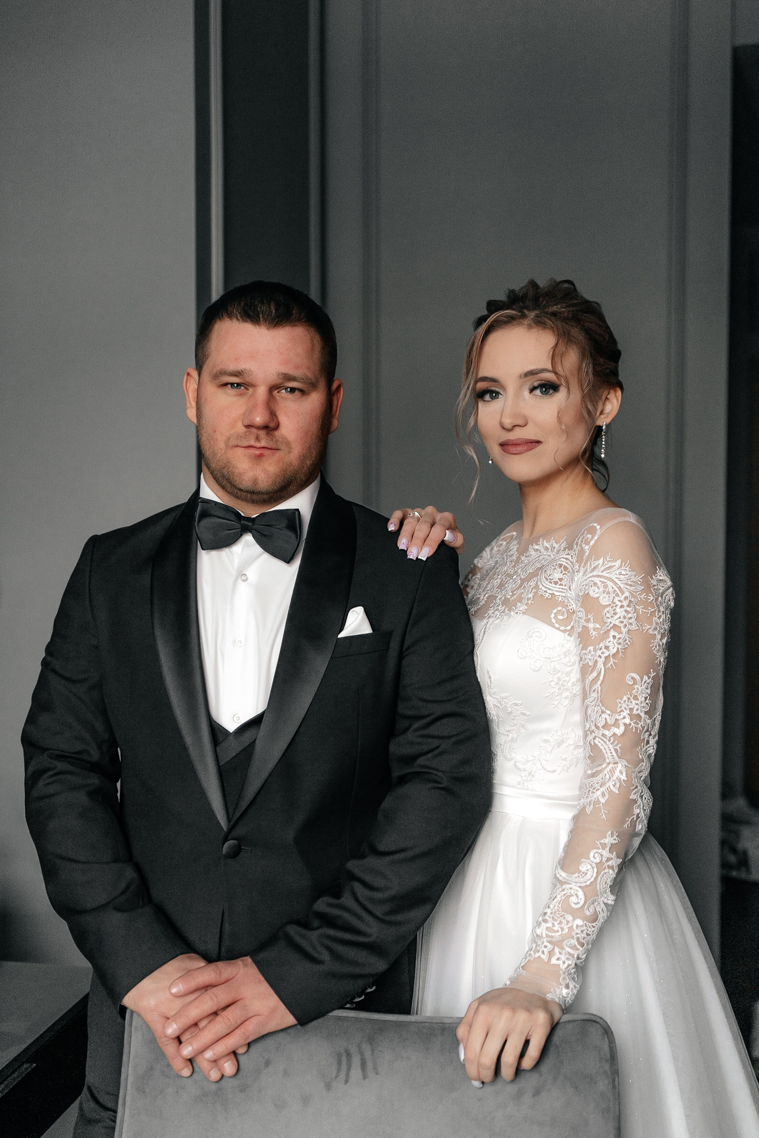 Свадебный портрет невесты и жениха в отеле с серыми стенами