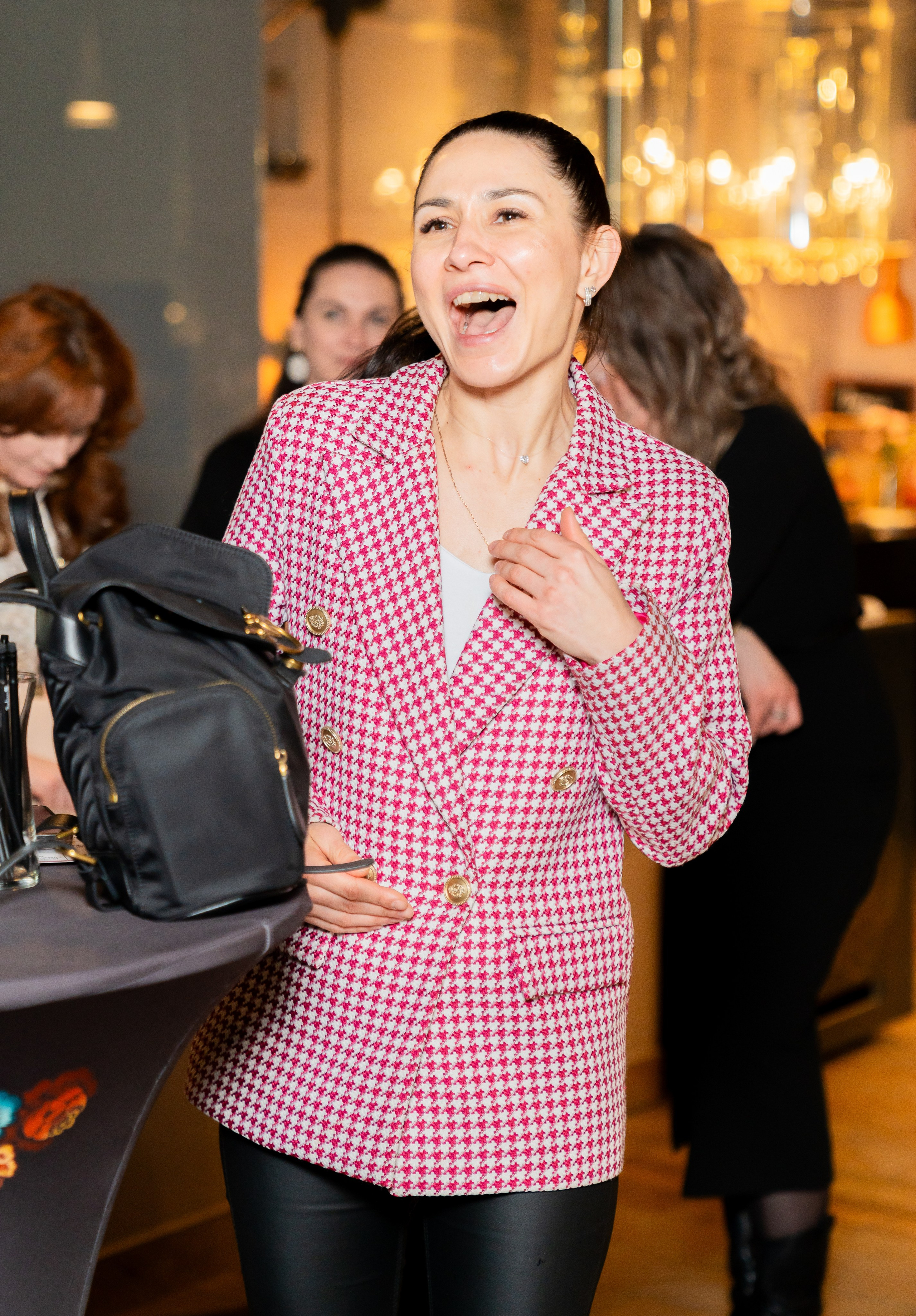 Радостная победительница в розовом жакете смеётся и держит руку на груди после выигрыша на розыгрыше в Radisson Sonya. Фото Евгения Мальцева (evrednix.ru).