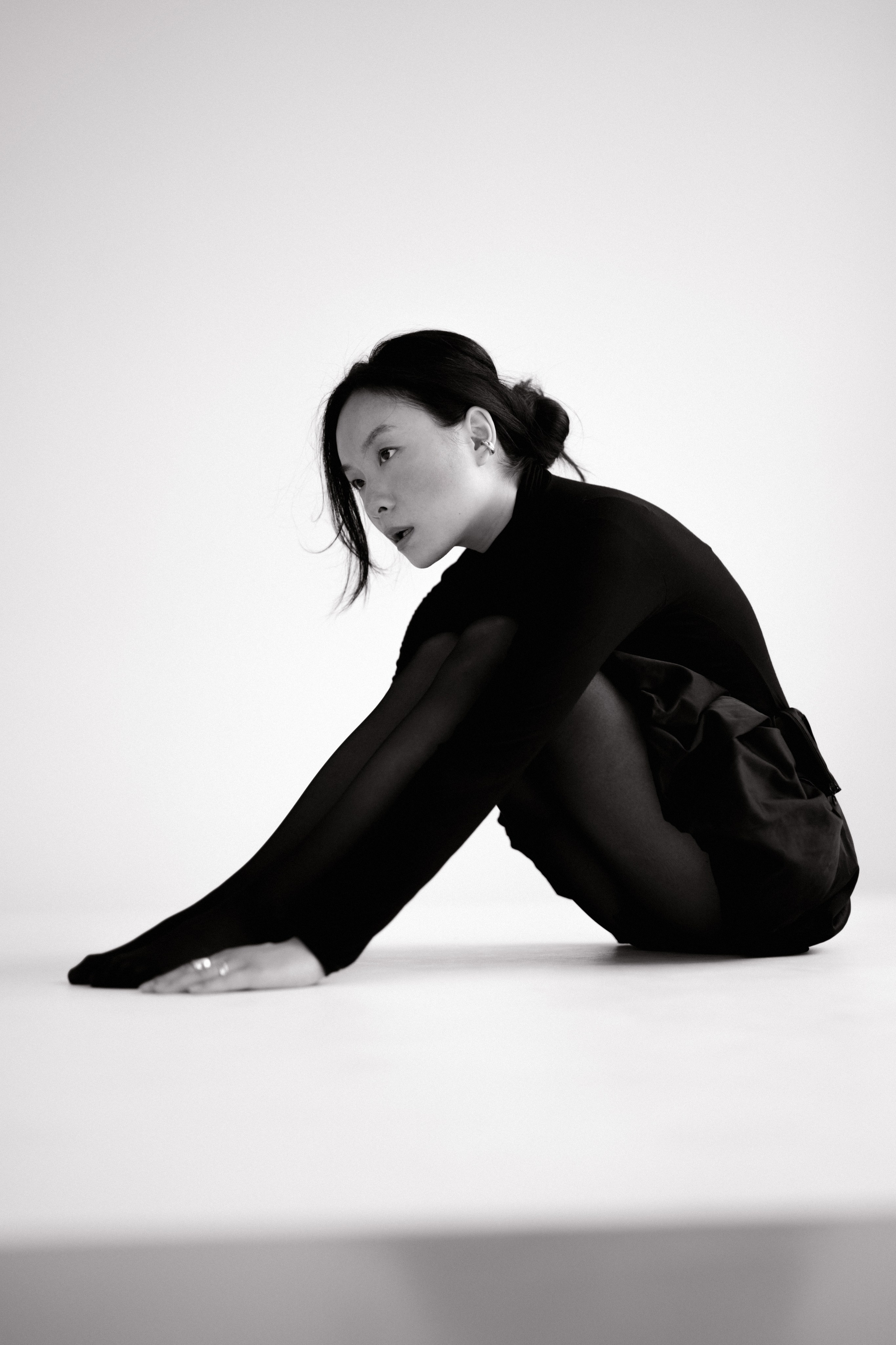 Чёрно-белый портрет модели в чёрной одежде, сидящей на полу в студии в Санкт-Петербурге