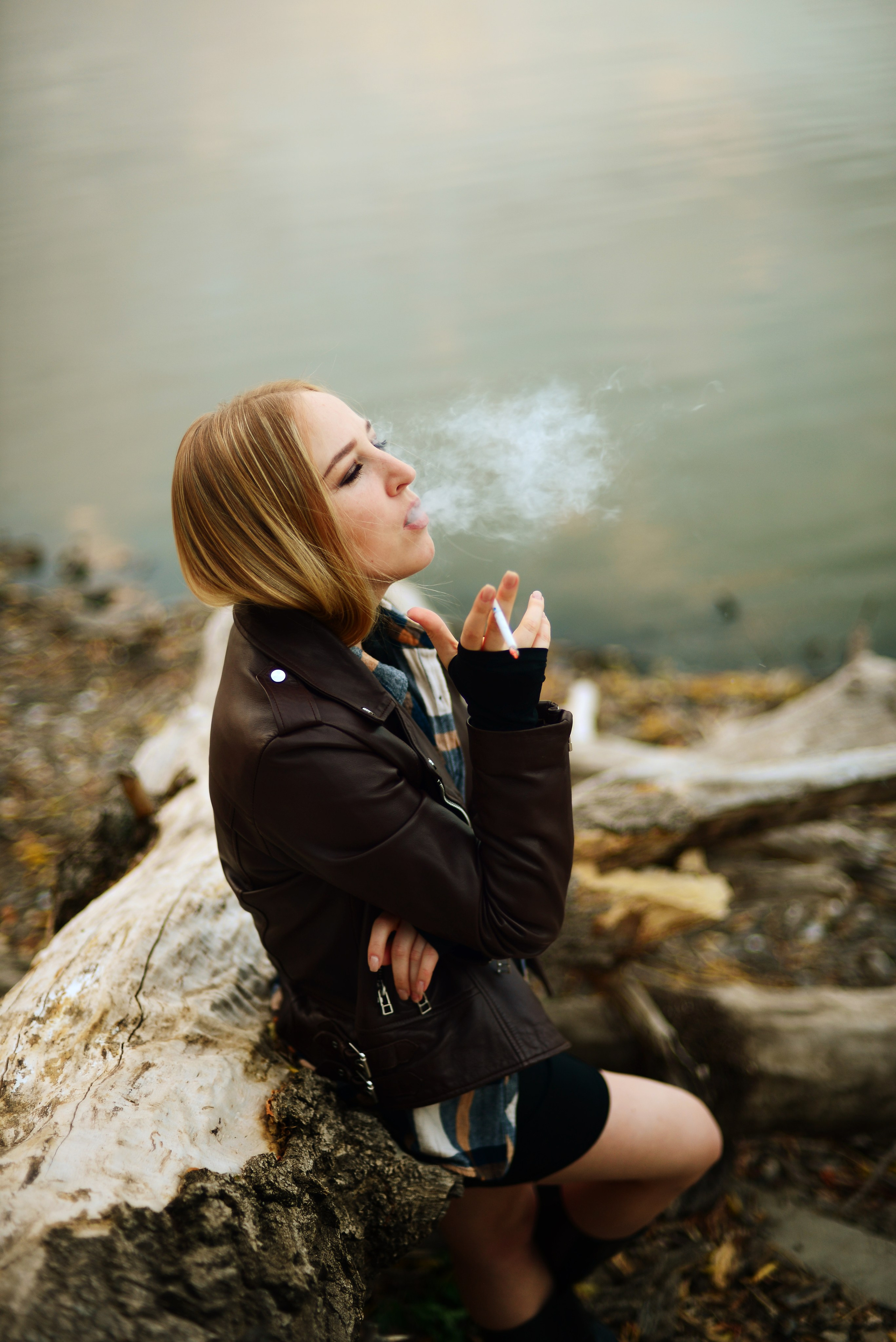 Осенняя фотосессия красивой девушки на Луганском море, которая красиво выпускает дым от сигареты.