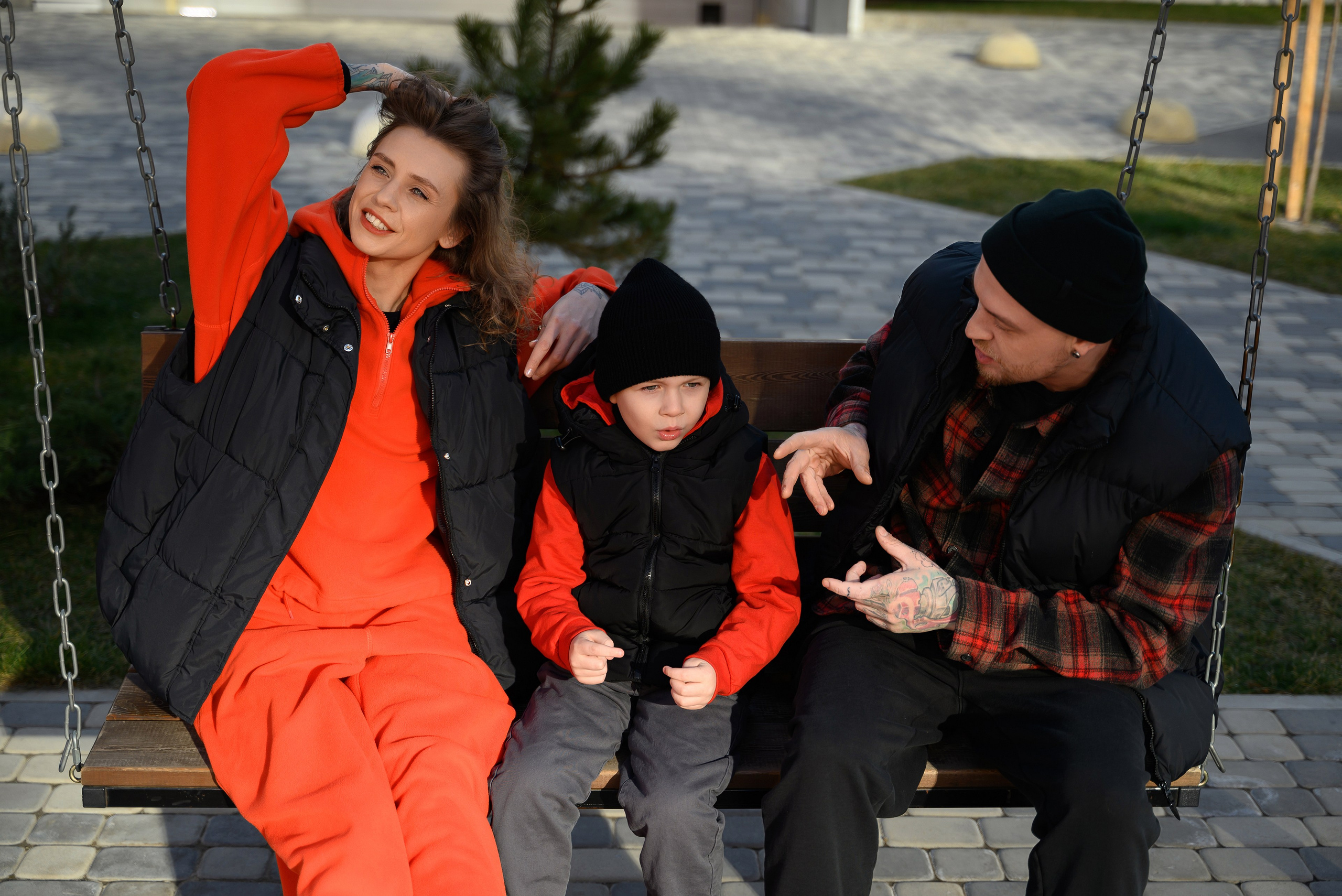 Фотография как мама, папа и ребенок качаются на качелях.