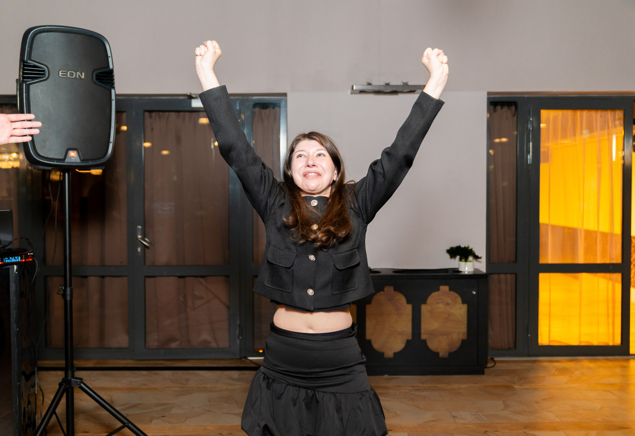 Энергичная девушка в чёрном укороченном жакете и мини-юбке зажигательно танцует под ведущего с микрофоном на вечеринке в Radisson Sonya. Фото Евгения Мальцева (evrednix.ru).