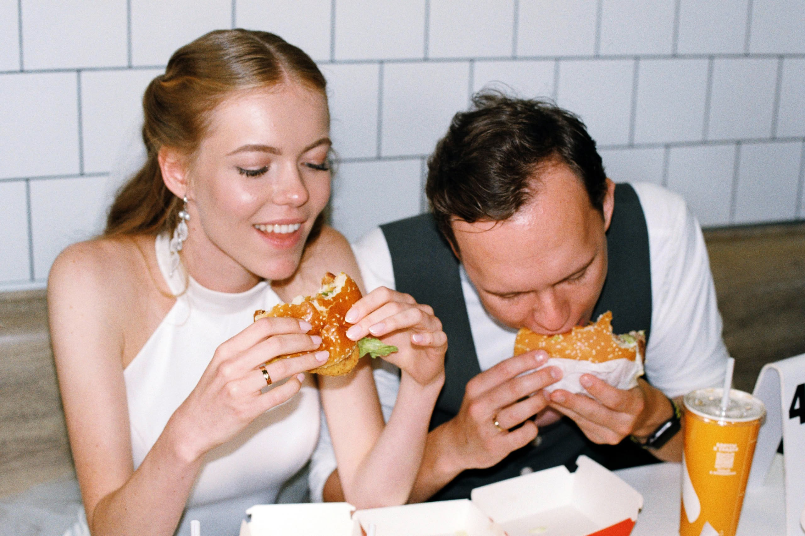 Пара ест бургеры во «Вкусно — и точка», непринуждённая сцена в свадебный день