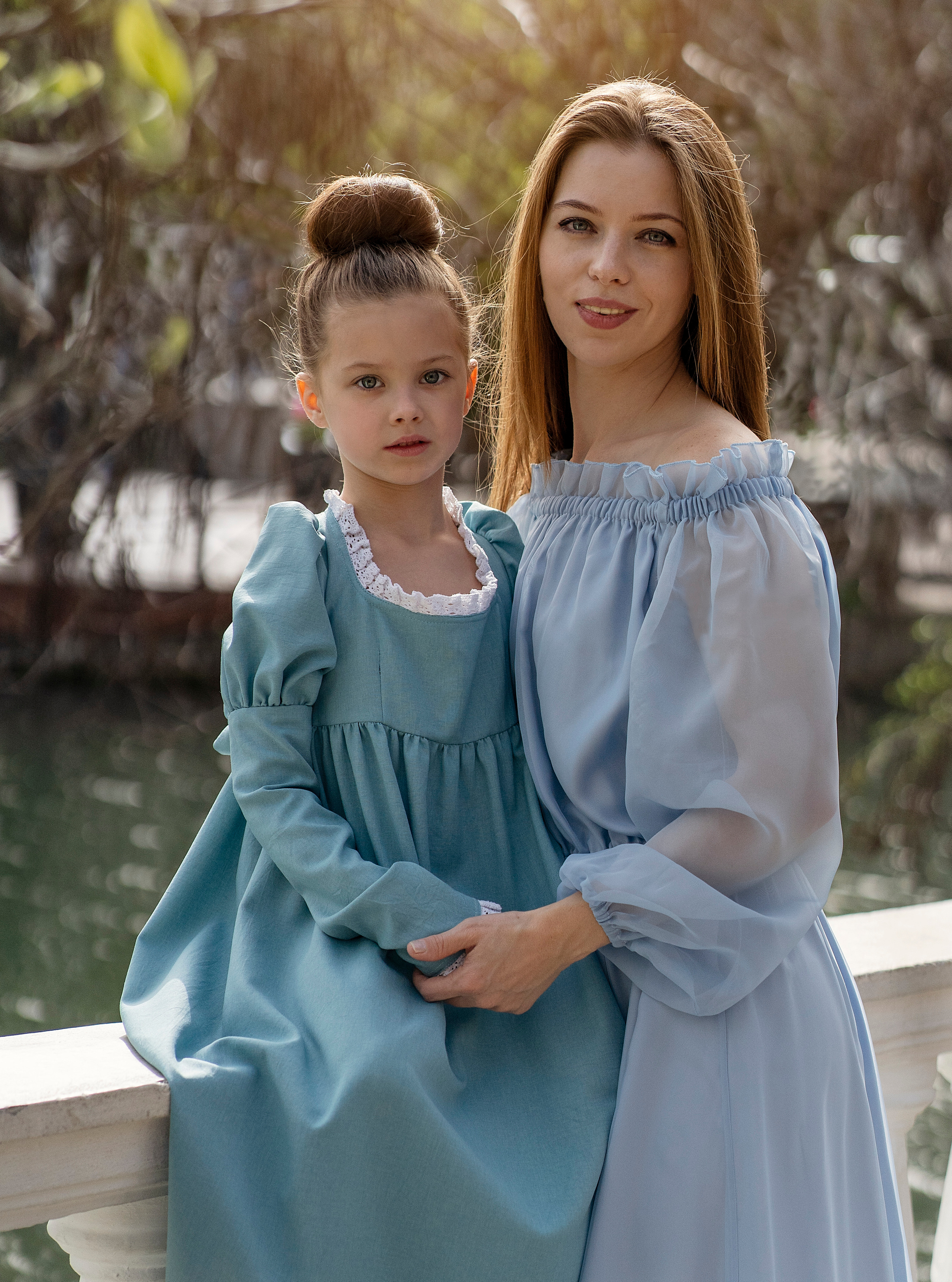 Мама и дочь позируют на фоне лебединого пруда.