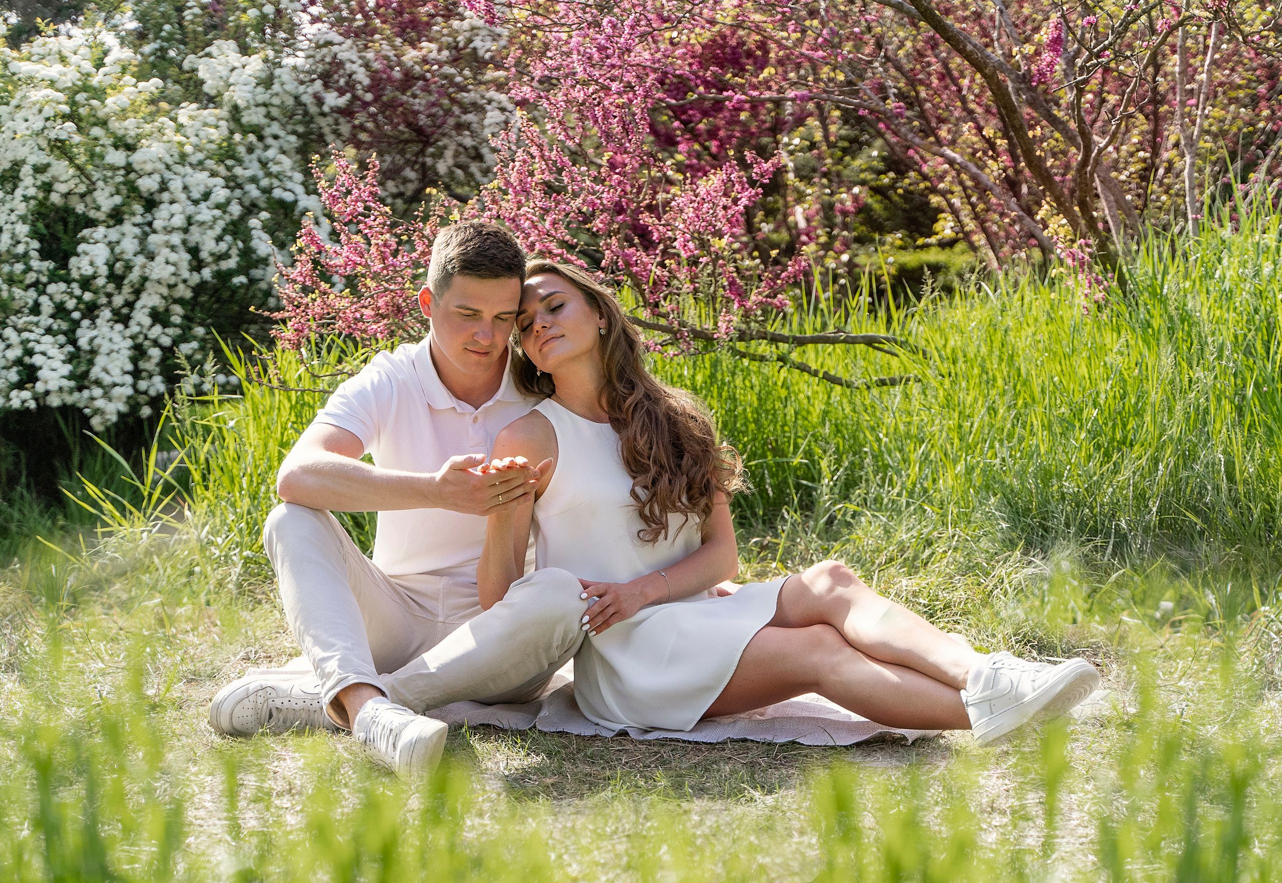 Влюбленные присели в тени цветущего персика.