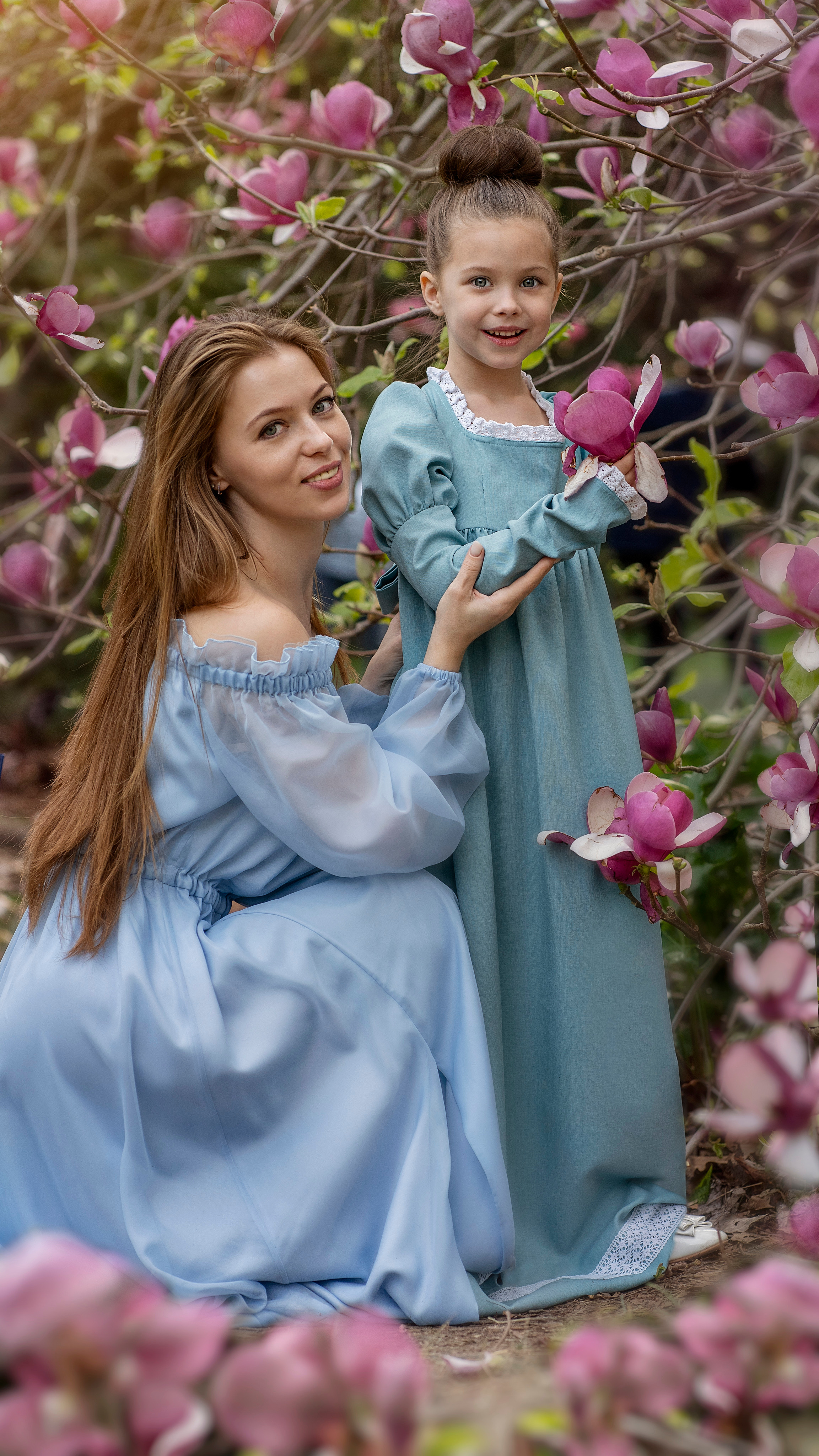Мама и дочь позируют на фоне цветущей магнолии в парке Южные Культуры.