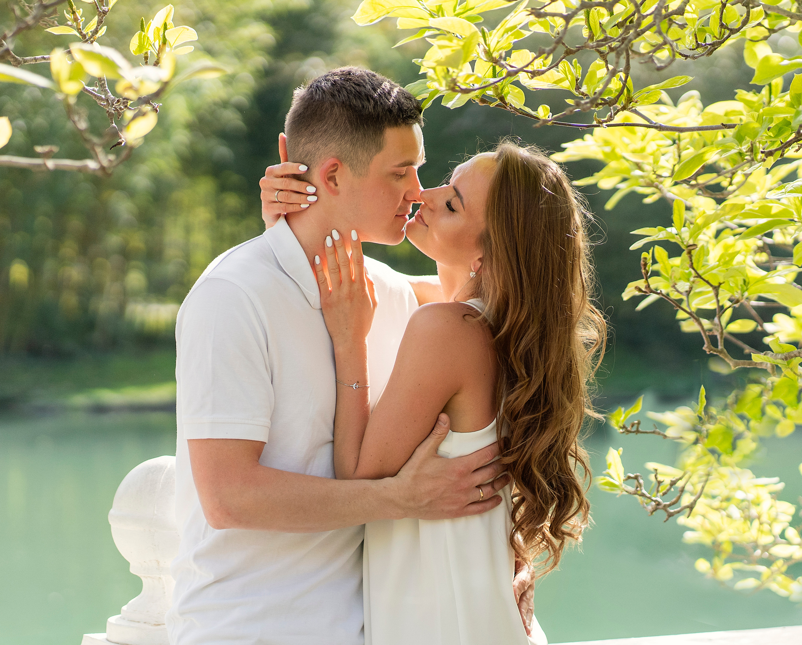 Влюбленная пара целуется на фоне пруда.