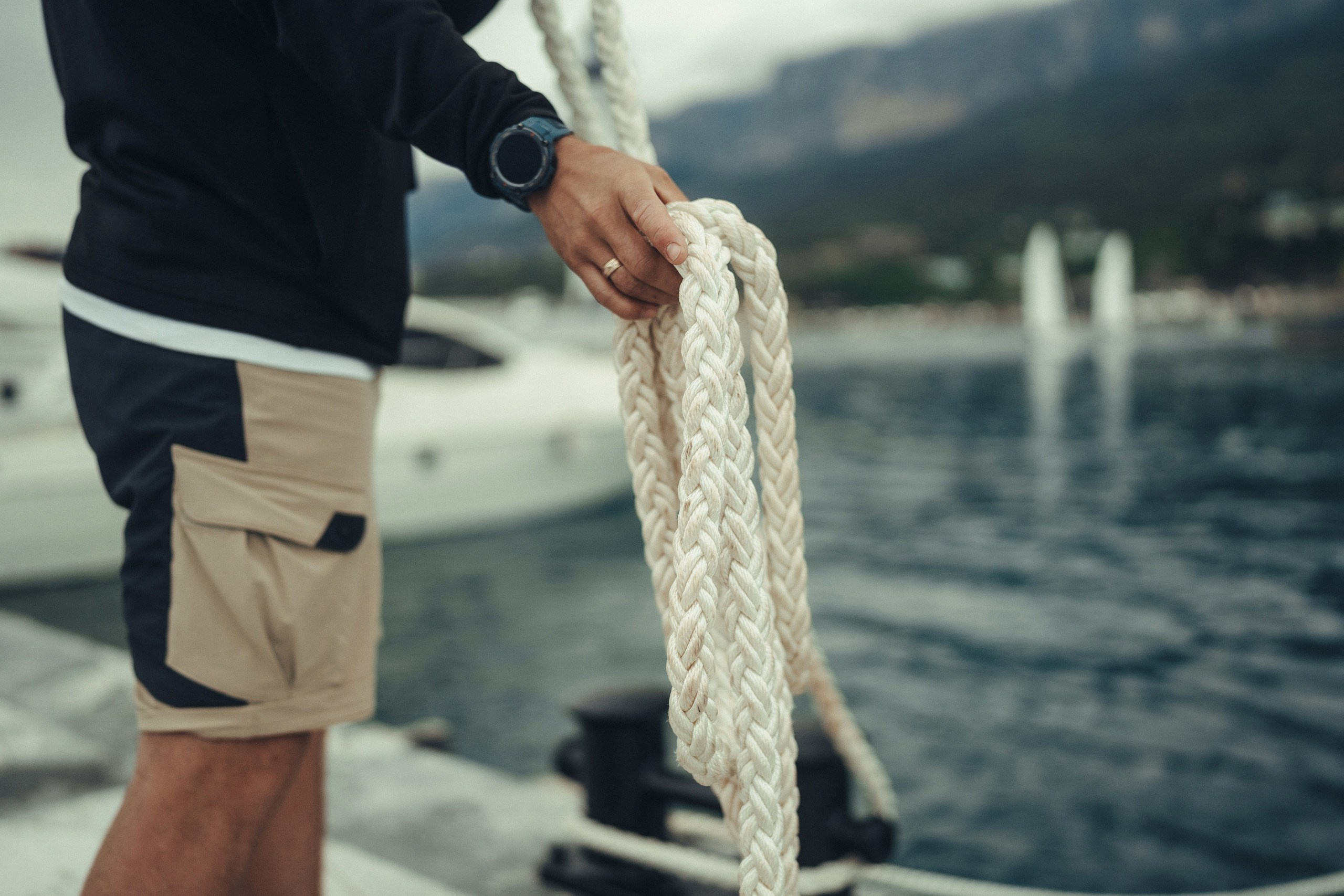 Репортажная фотосессия в Крыму: мужчина держит морской швартовый канат крупным планом на фоне моря.