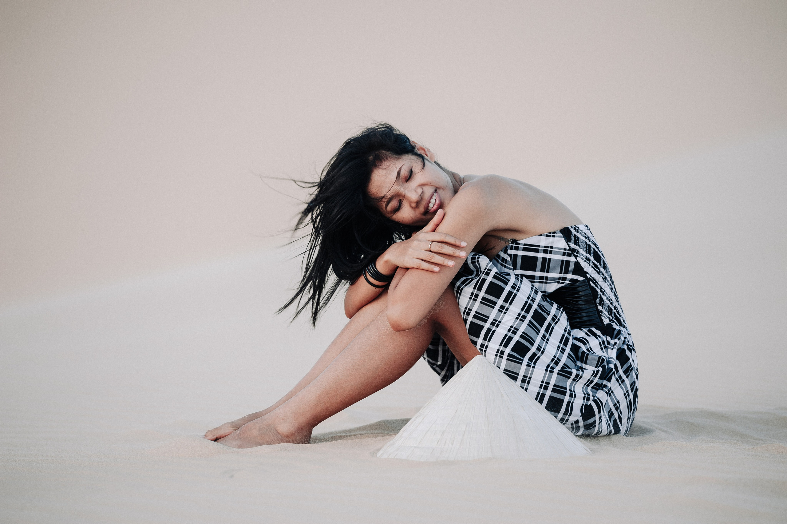 Молодая вьетнамская девушка сидит вечером в платье в дюнах Муине, Вьетнам