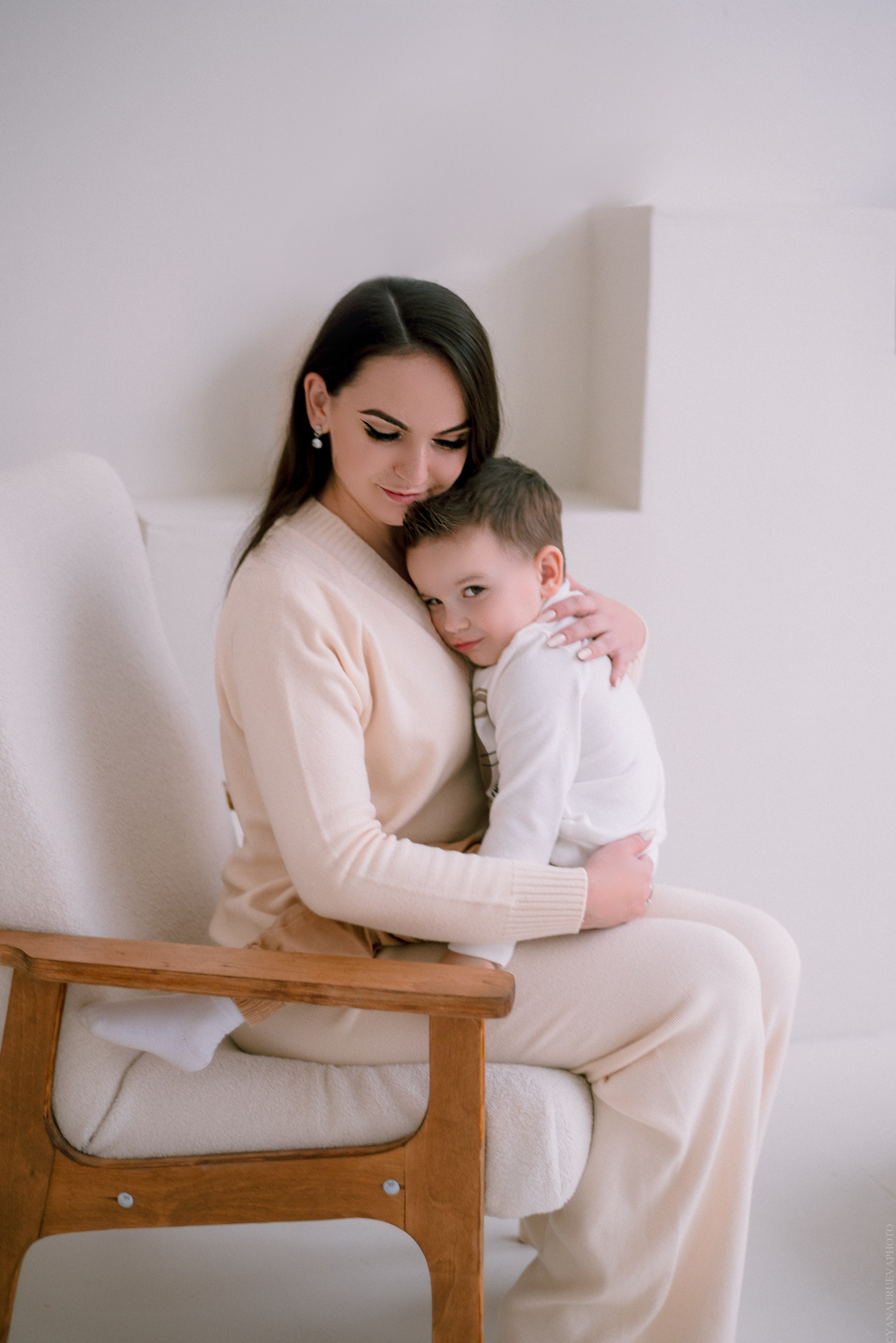 Мама сидит в кресле и обнимает сына