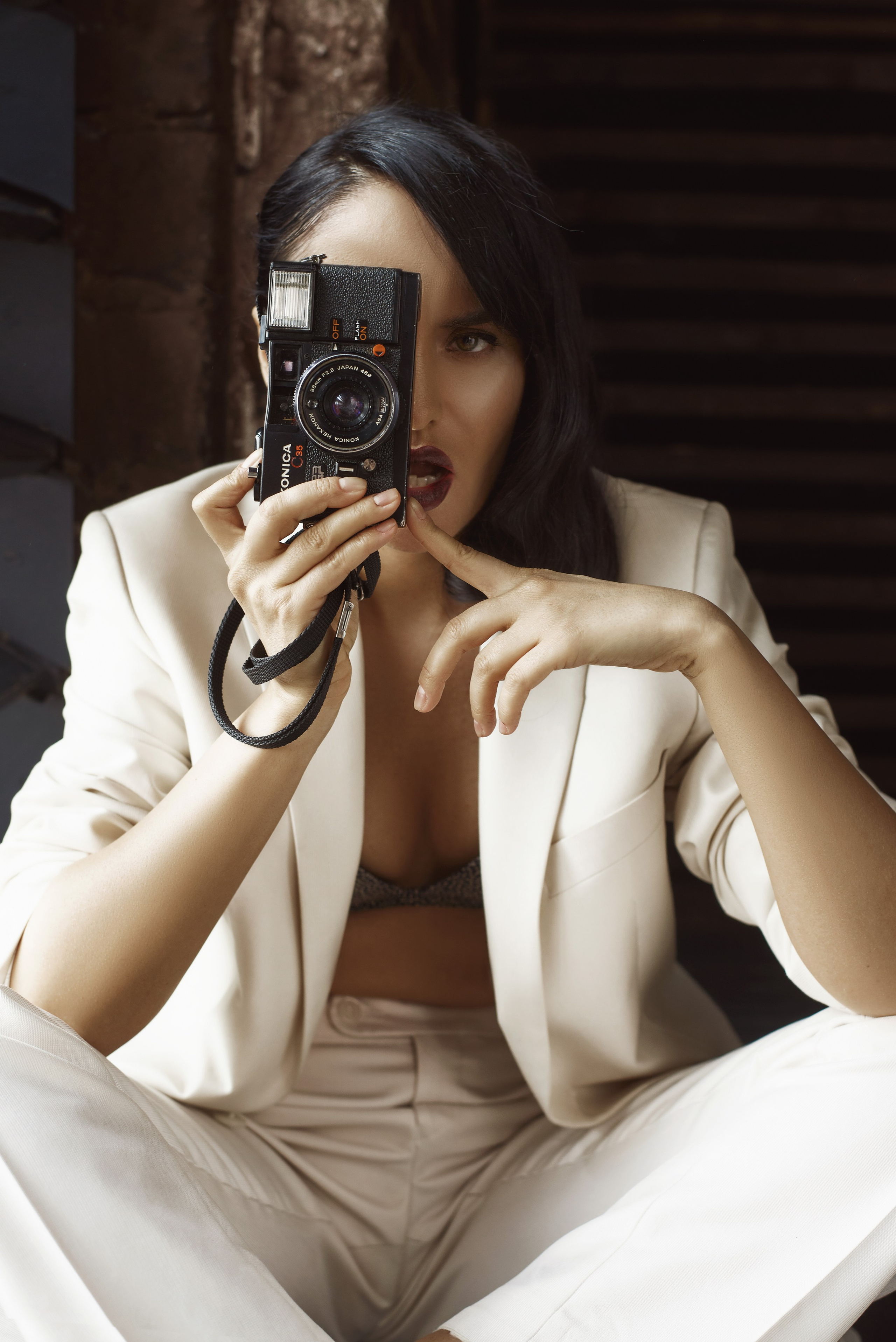 Фотосессия в брючном костюме брюнетки с ретро фотокамерой