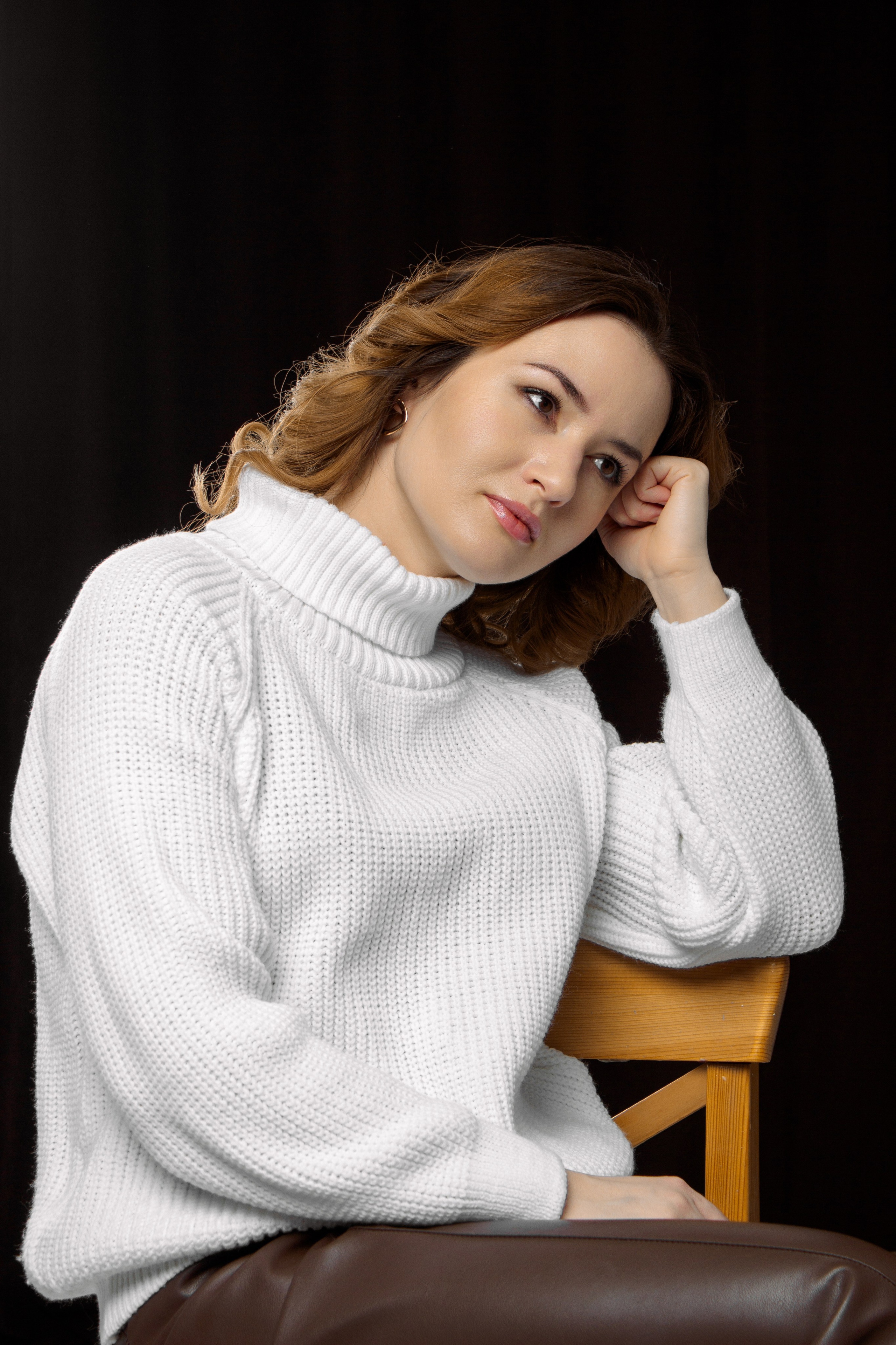портрет девушки в белом свитере на черном фоне