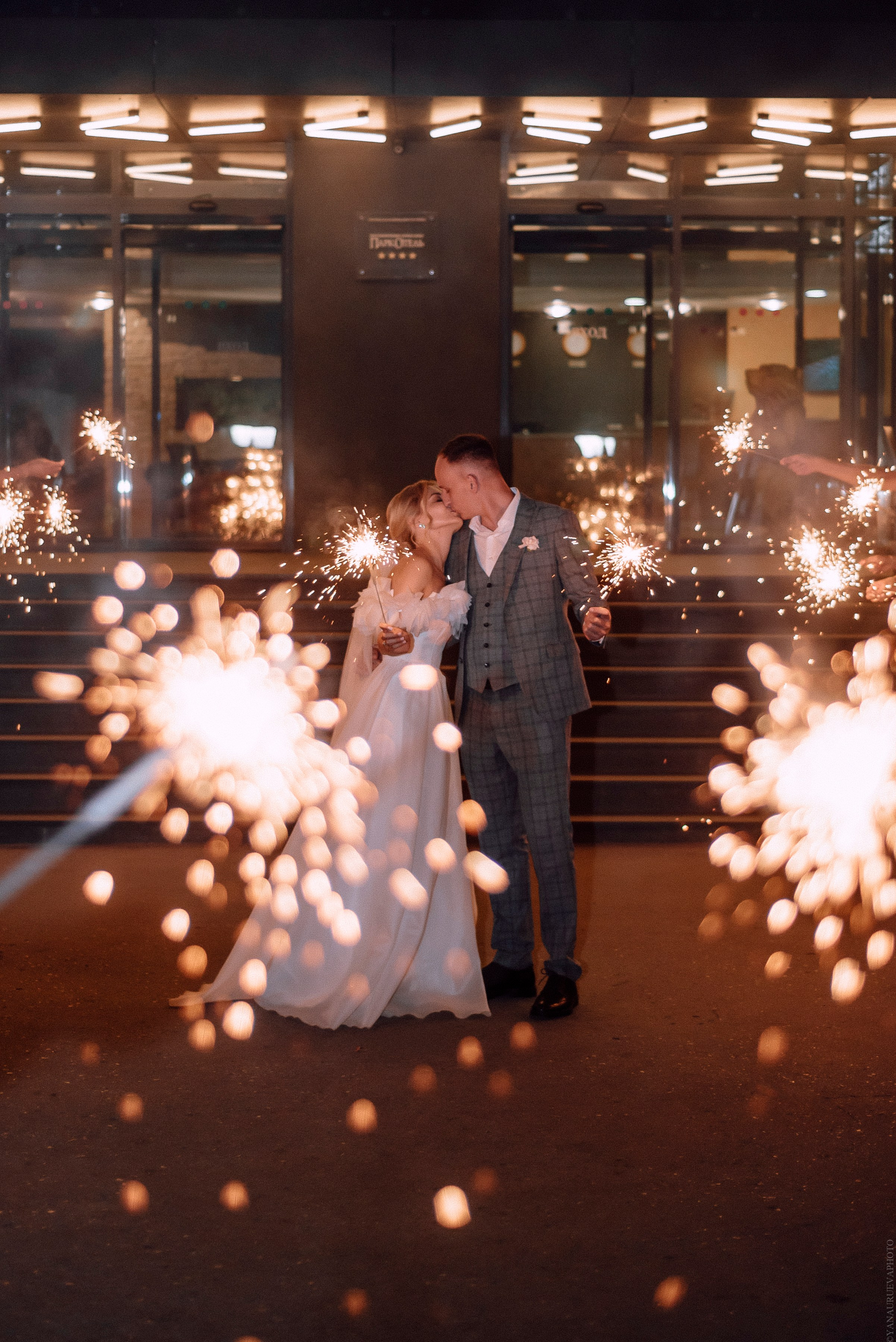 Молодожены целуются на фоне бенгальских огней, финал свадьбы