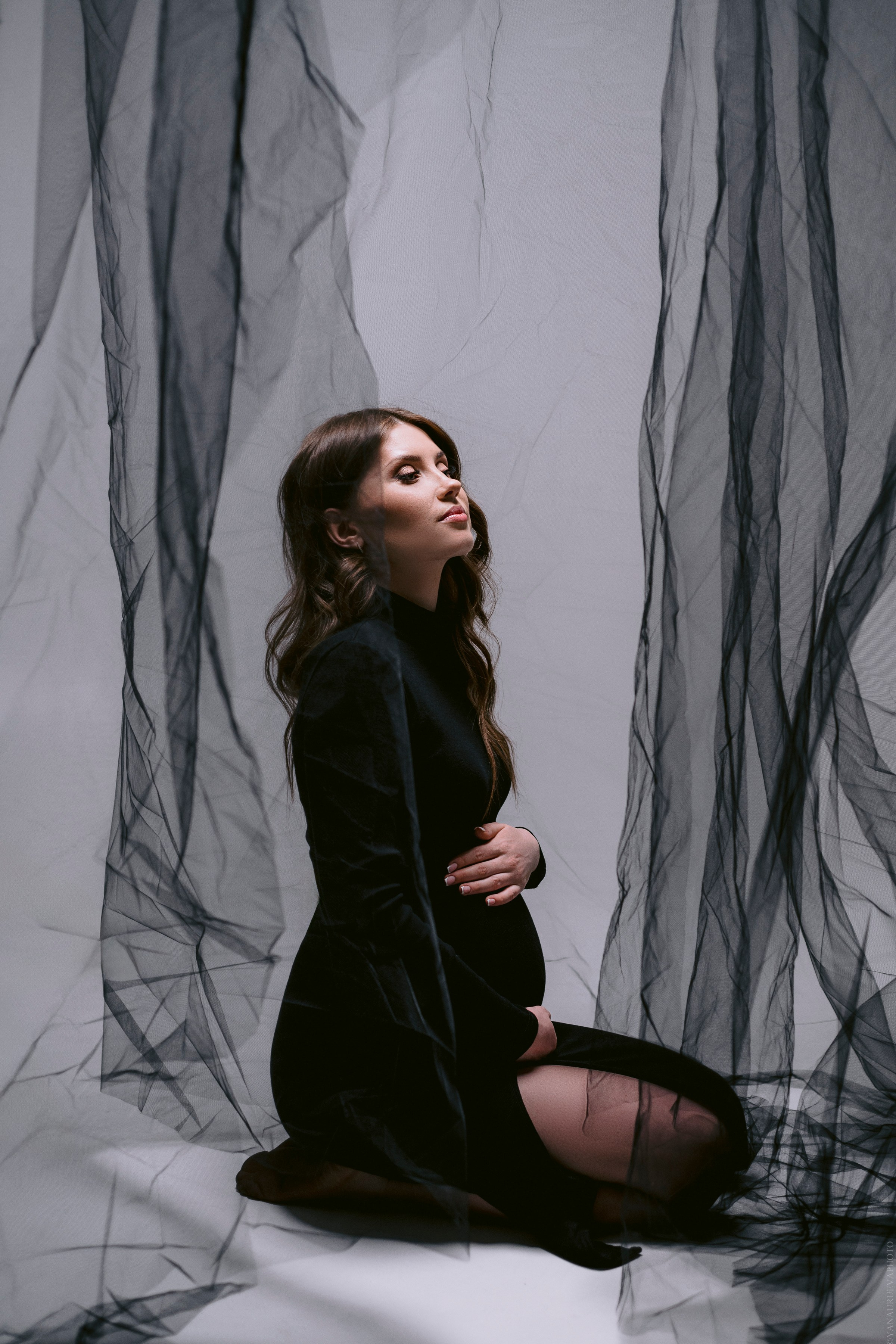 беременная девушка в черном платье с черной вуалью