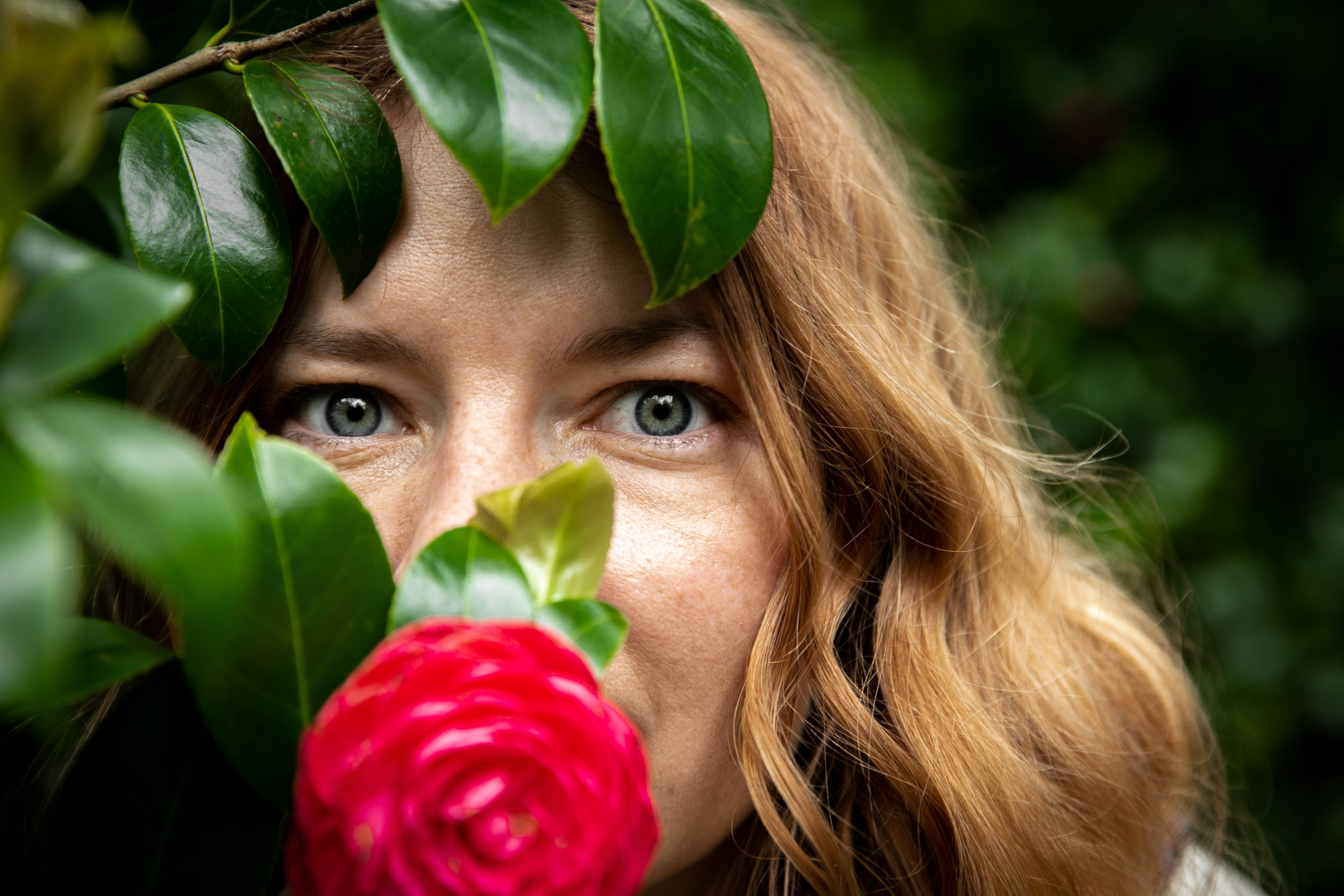 A serene moment of a woman surrounded by colourful flowers on the Azores, with the natural beauty of the landscape all around her
