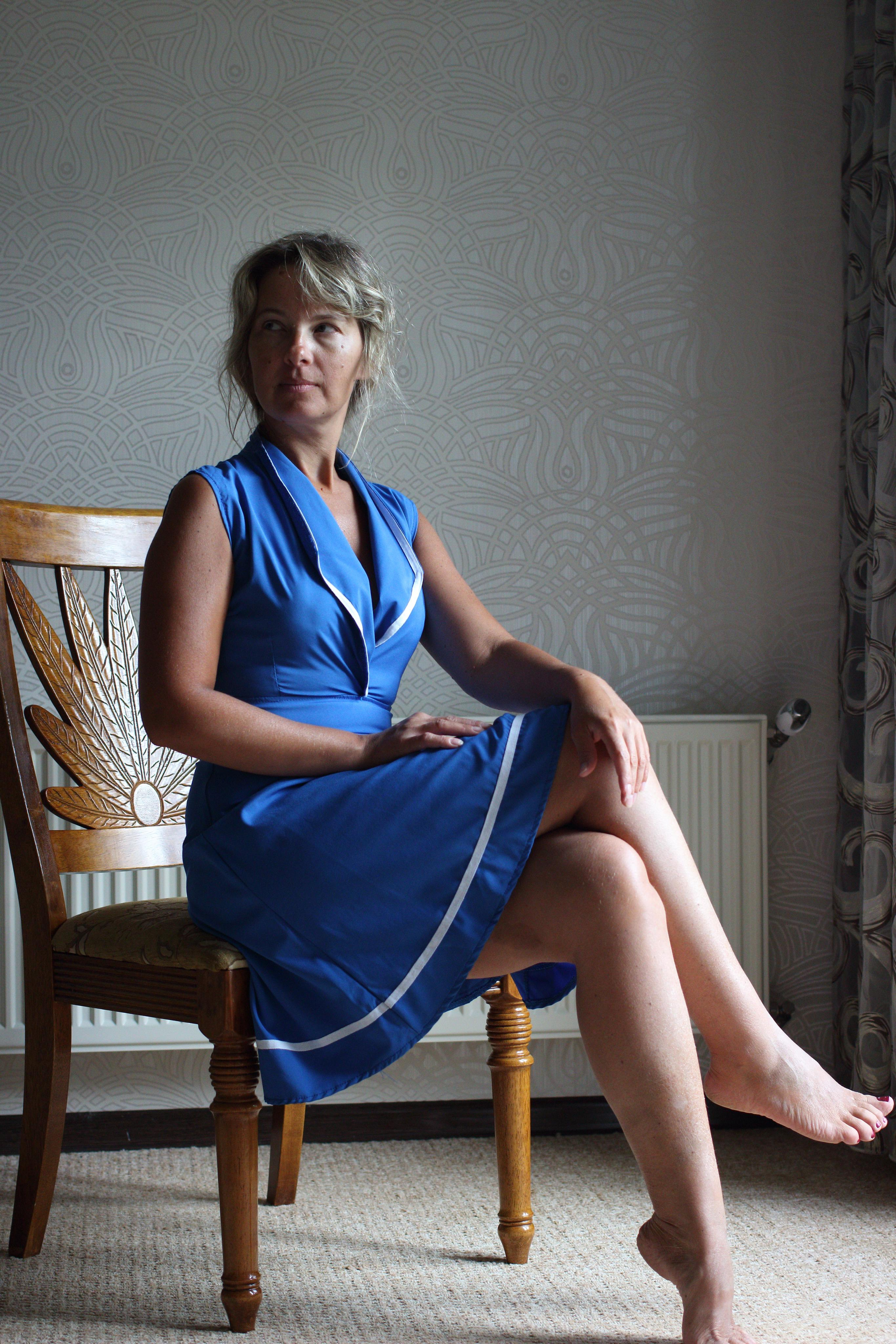 девушка сидит на стуле у окна в синем платье