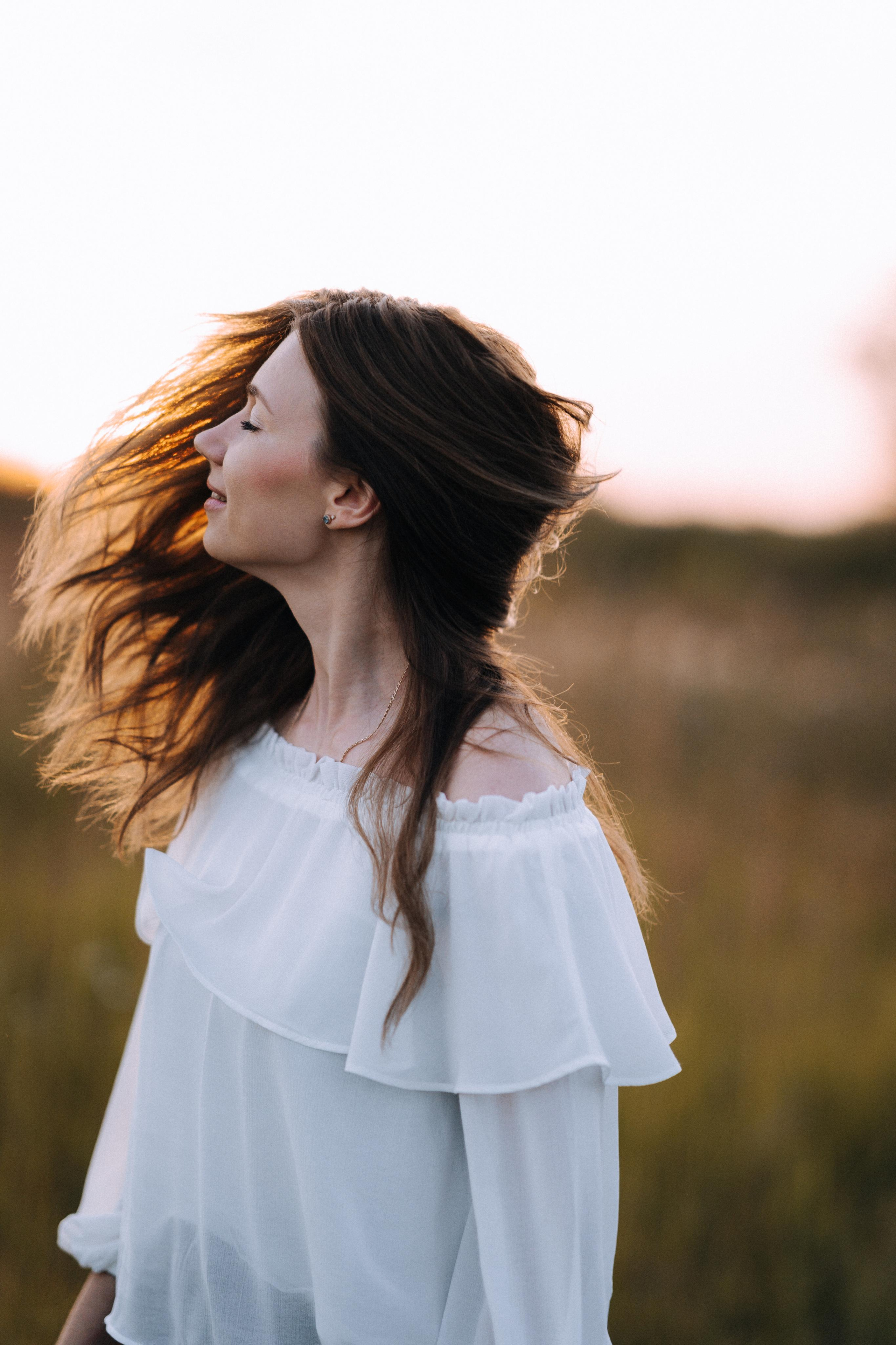 Нежный женский портрет с разлетающимися волосами на солнце.