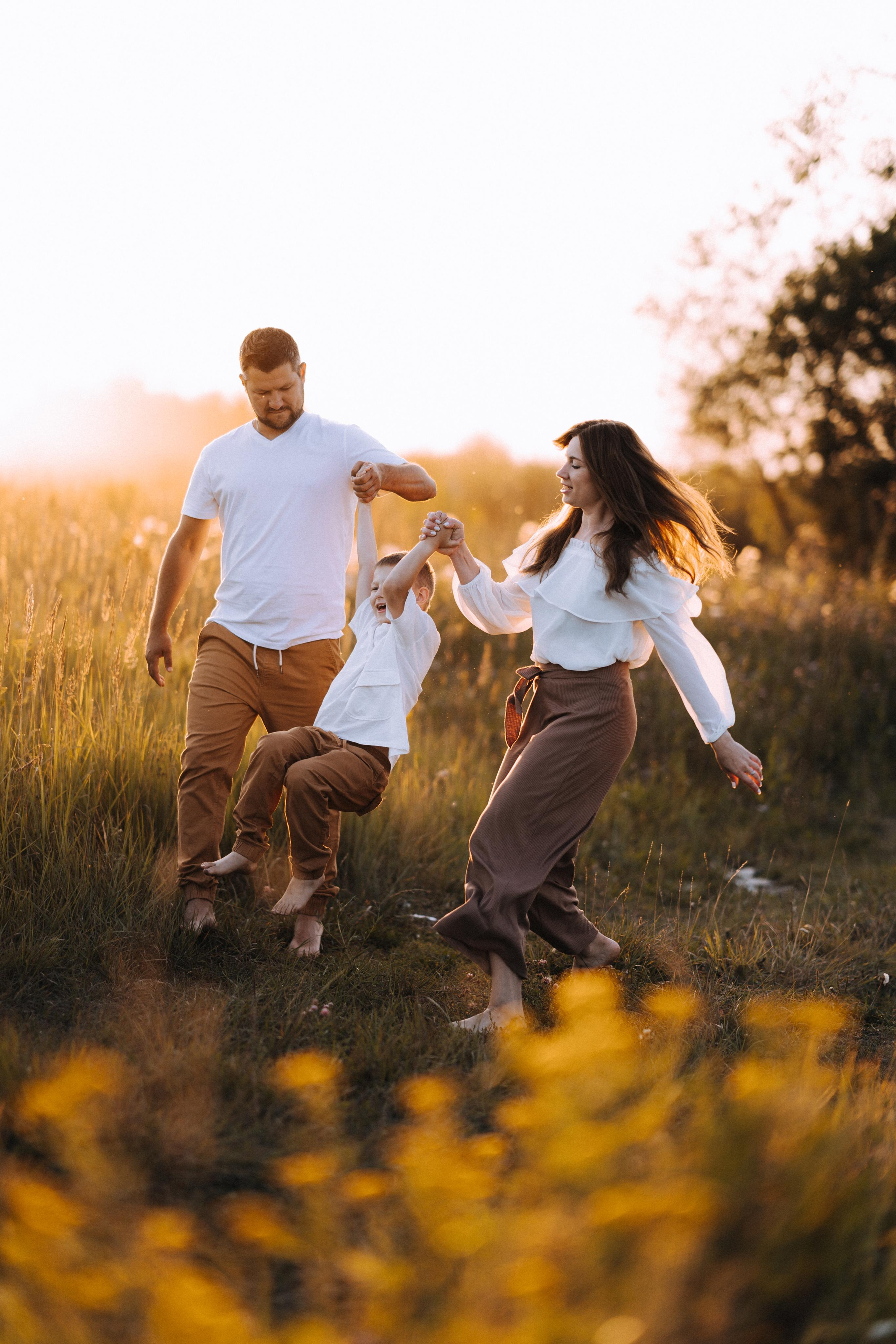 Семья бежит по полю в стильной одежде.