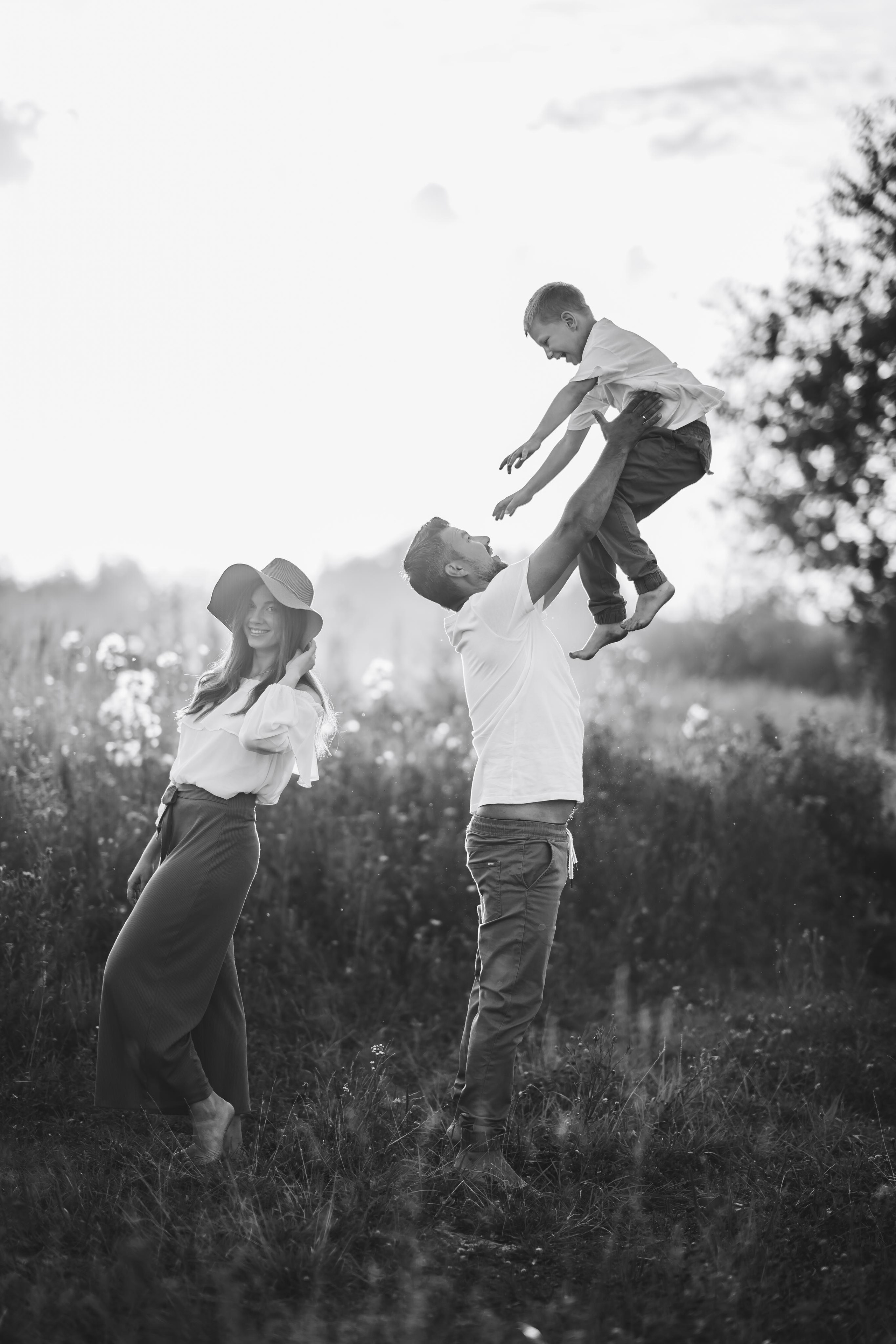 Отец подбрасывает сына в небо, мальчик смеётся и счастлив. 