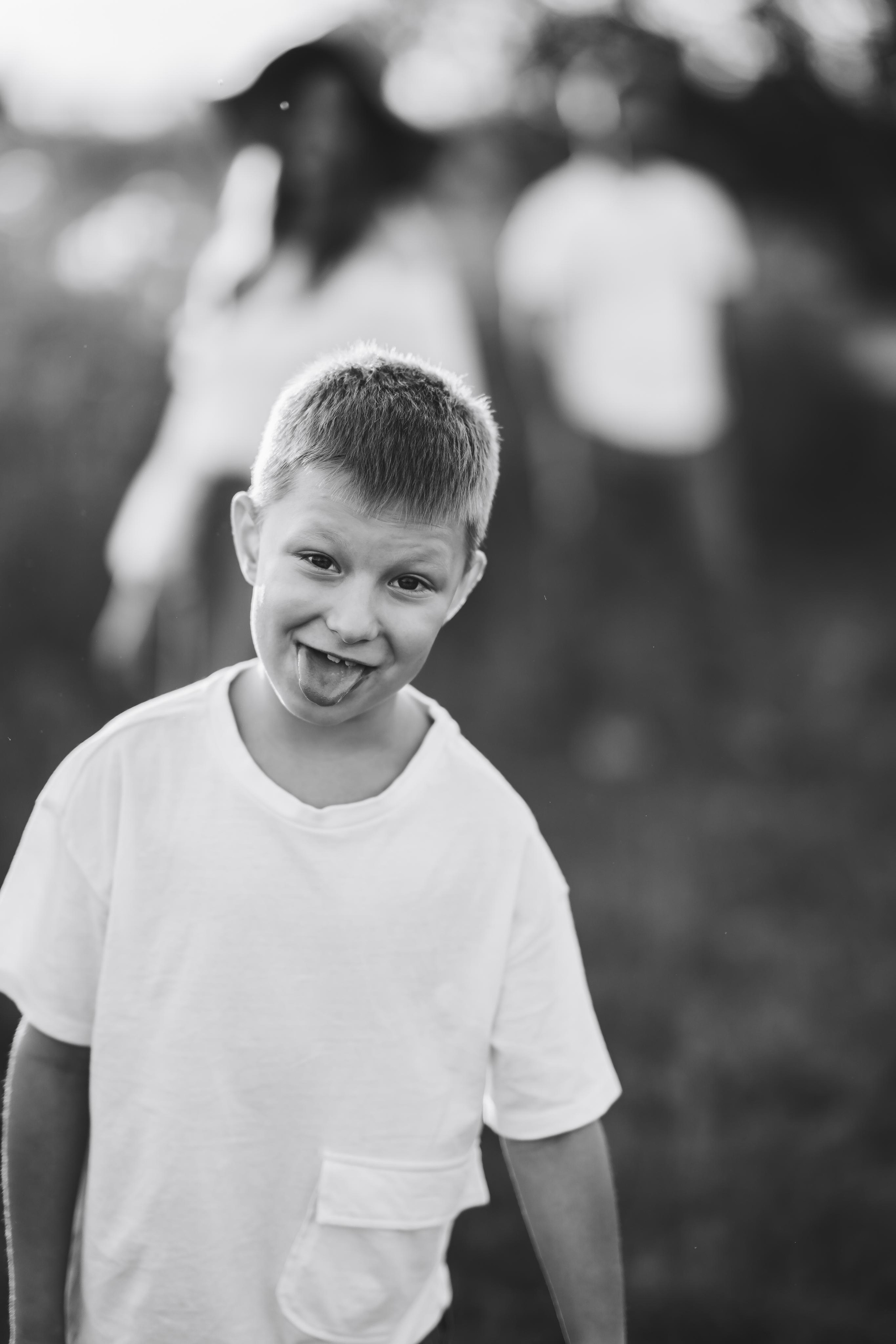 Портрет мальчика показывающего язык, позади мама и папа.