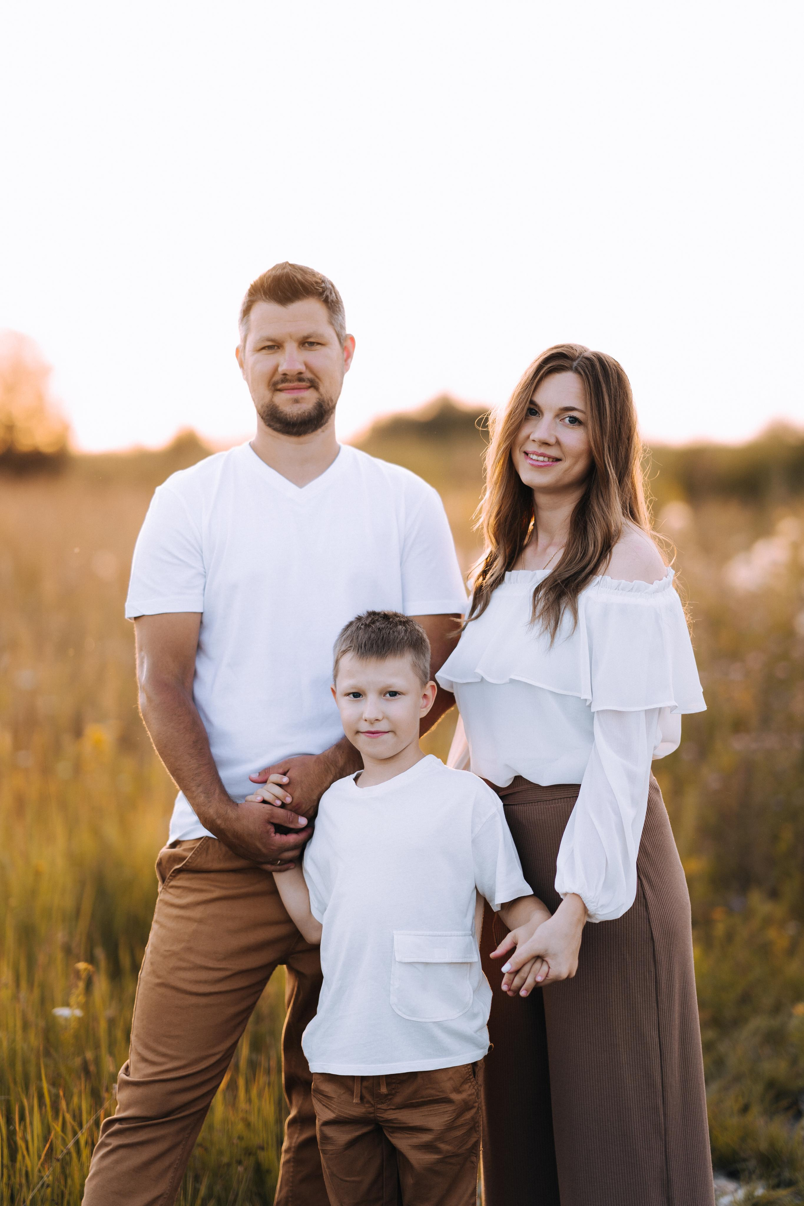 Счастливые папа, мама и сын. Все улыбаются и смотрят в камеру.