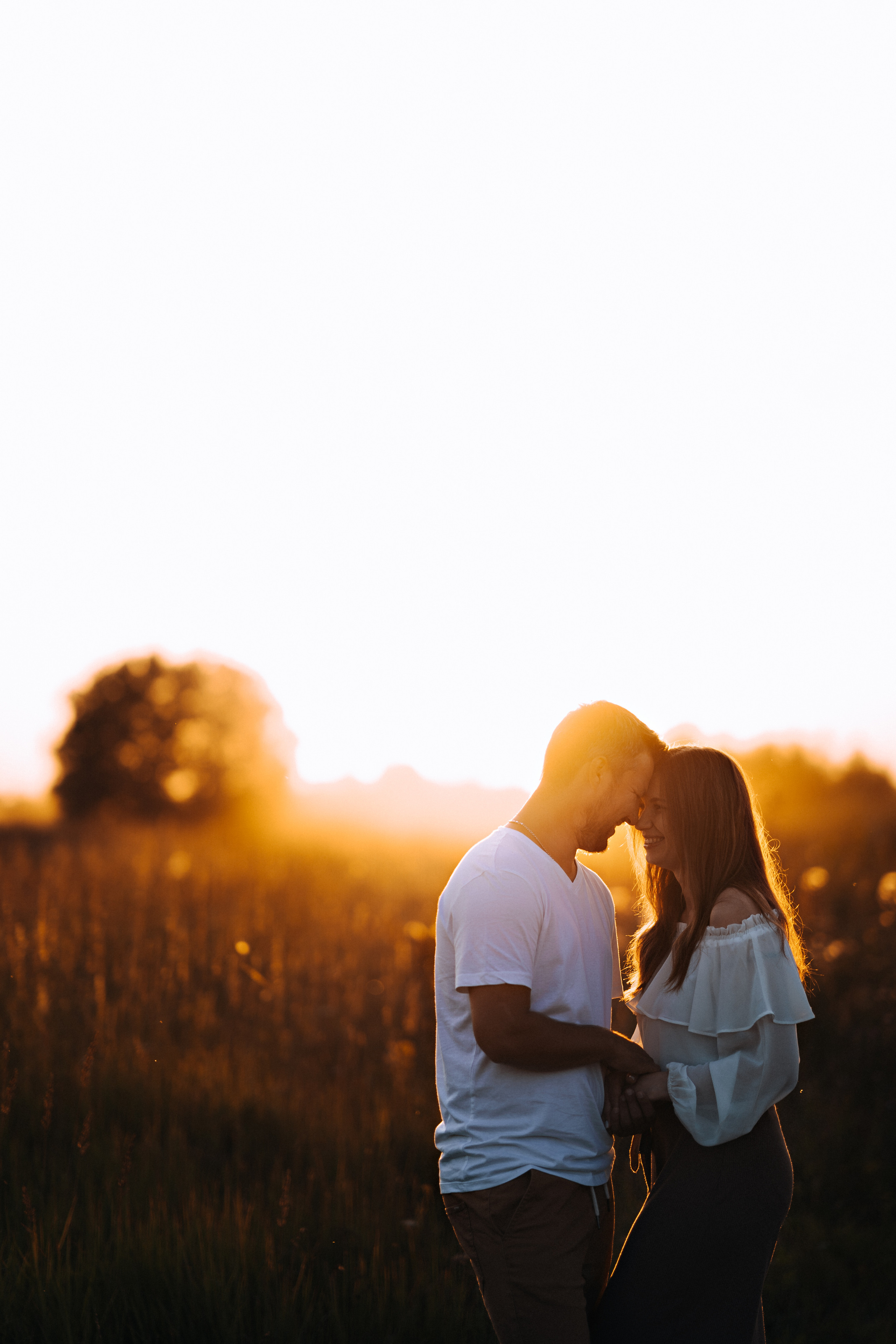 Пара на закате яркого солнца. Обнимаются и любят друг друга.