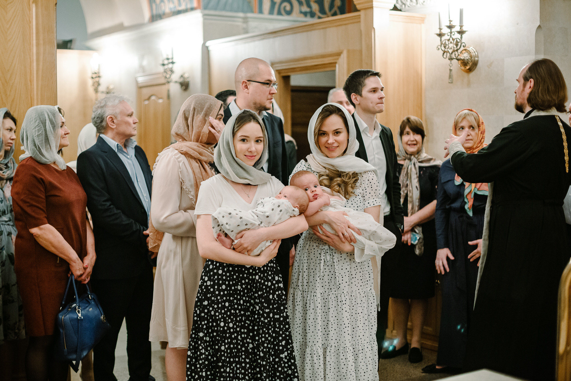 Мамы держат своих малышей на руках в храме перед крещением