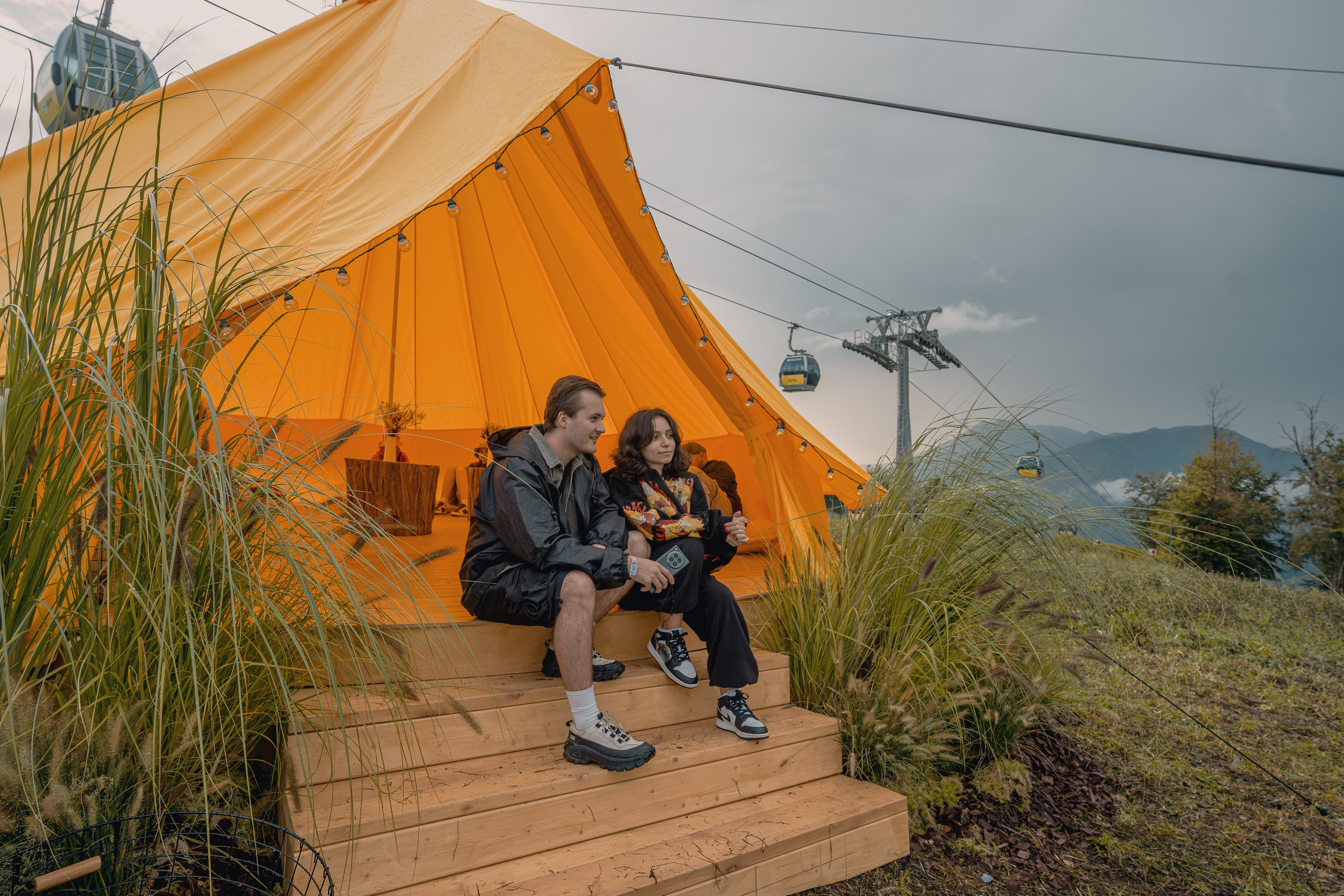 Общее фото палатки с парой которая смотрит на телефон