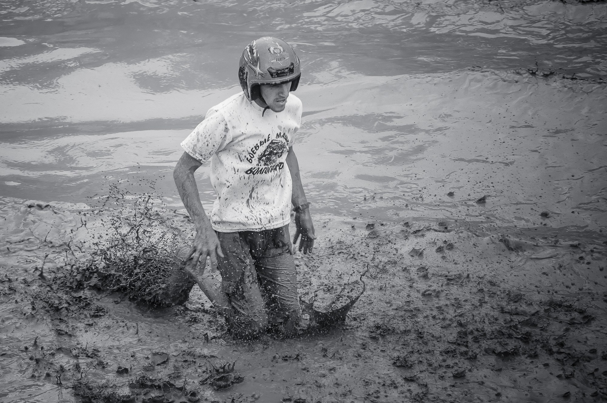 Водитель застрявшего автомобиля стоит по колено в грязи