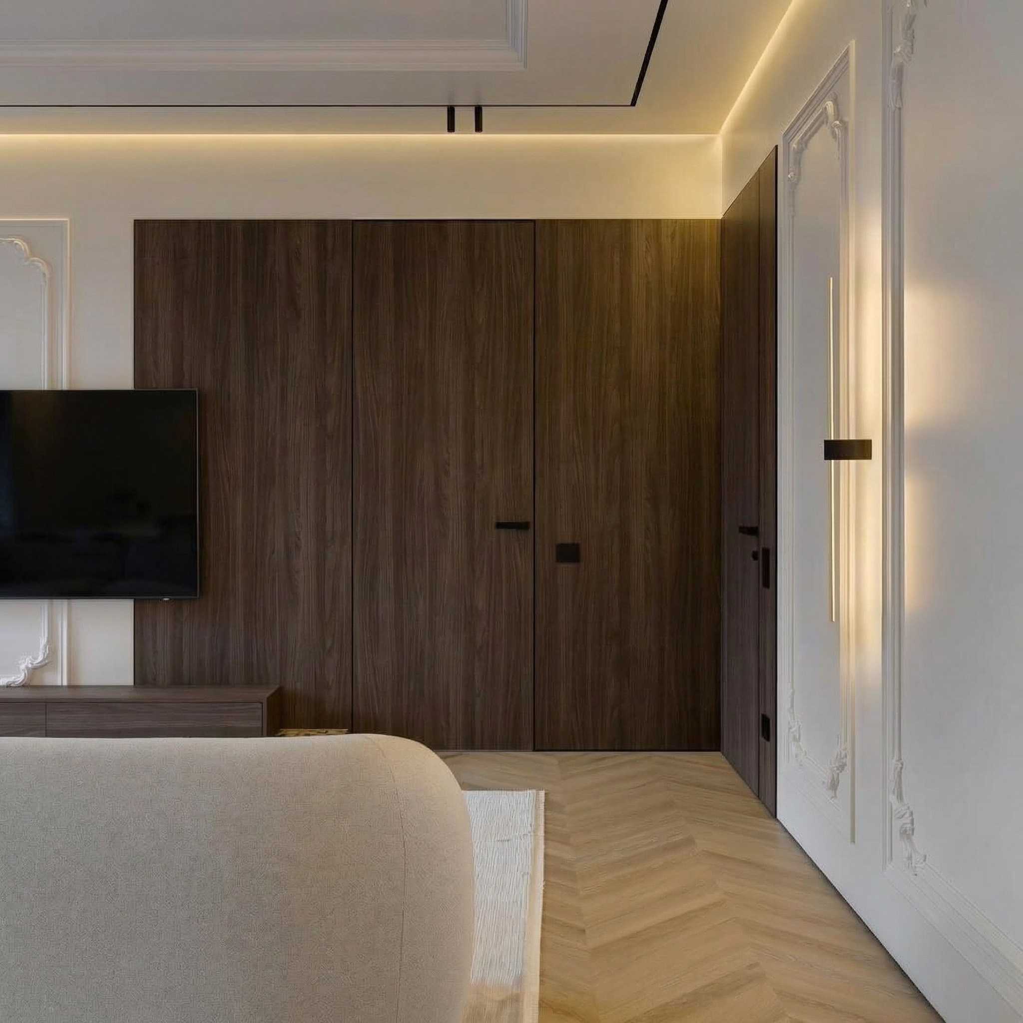 Интерьер гостиной от Валерии Котович: двери скрытого монтажа в отделке под дерево, белые стены с неоклассическими молдингами, паркет «французская елка» и современное дизайнерское освещение.