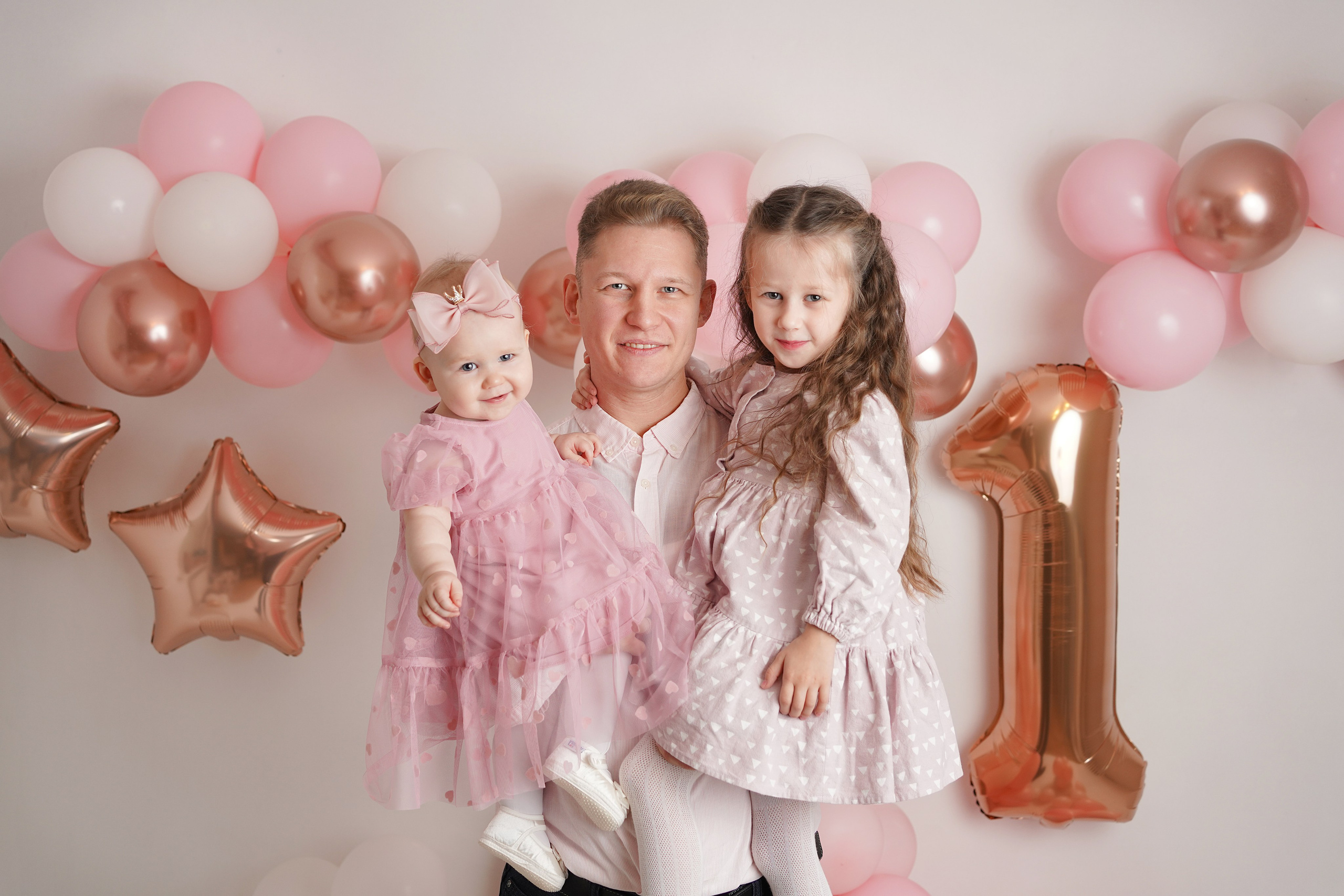 Папа держит на руках двух своих дочерей. Они приехали с родителями на фотосессию.