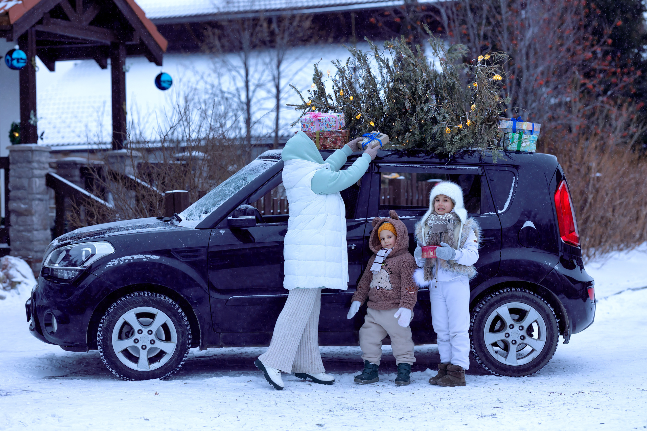 Новогодняя машина с ёлкой на крыше. Счастливая семья в машине дарит подарки
