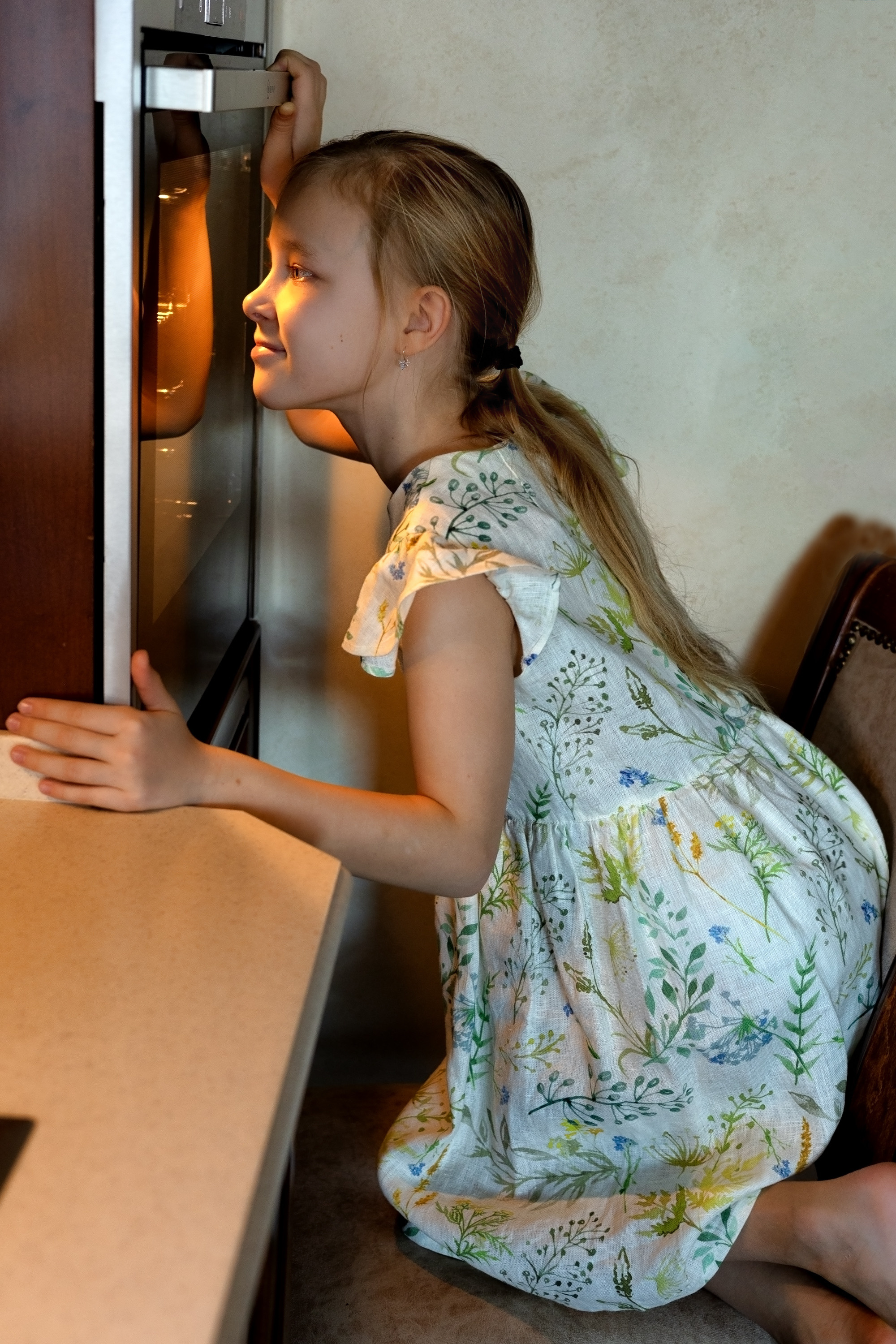 девочка кулинар заглядывает в духовку где печет торт