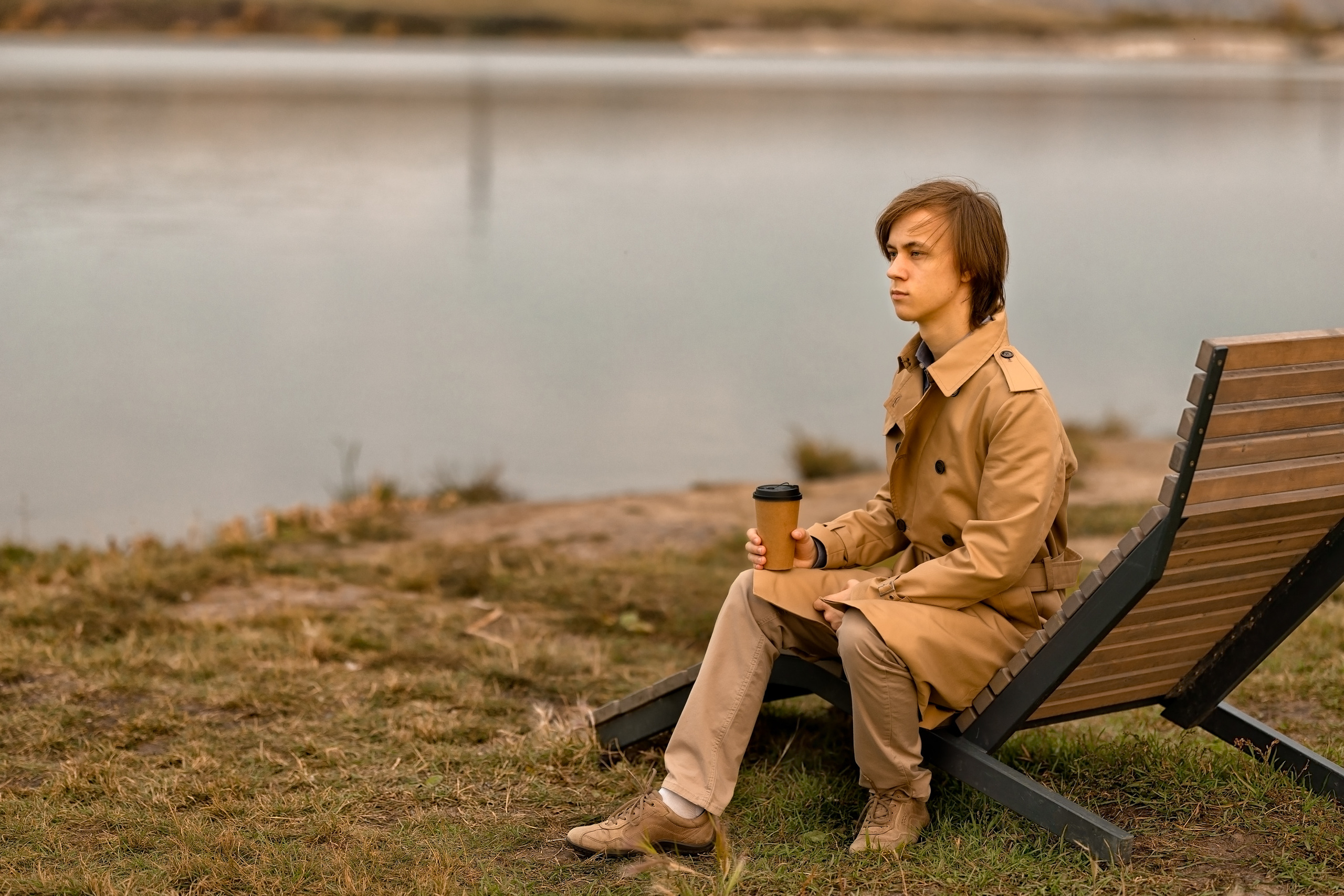 Мужчина возле озера осенью пьет кофе