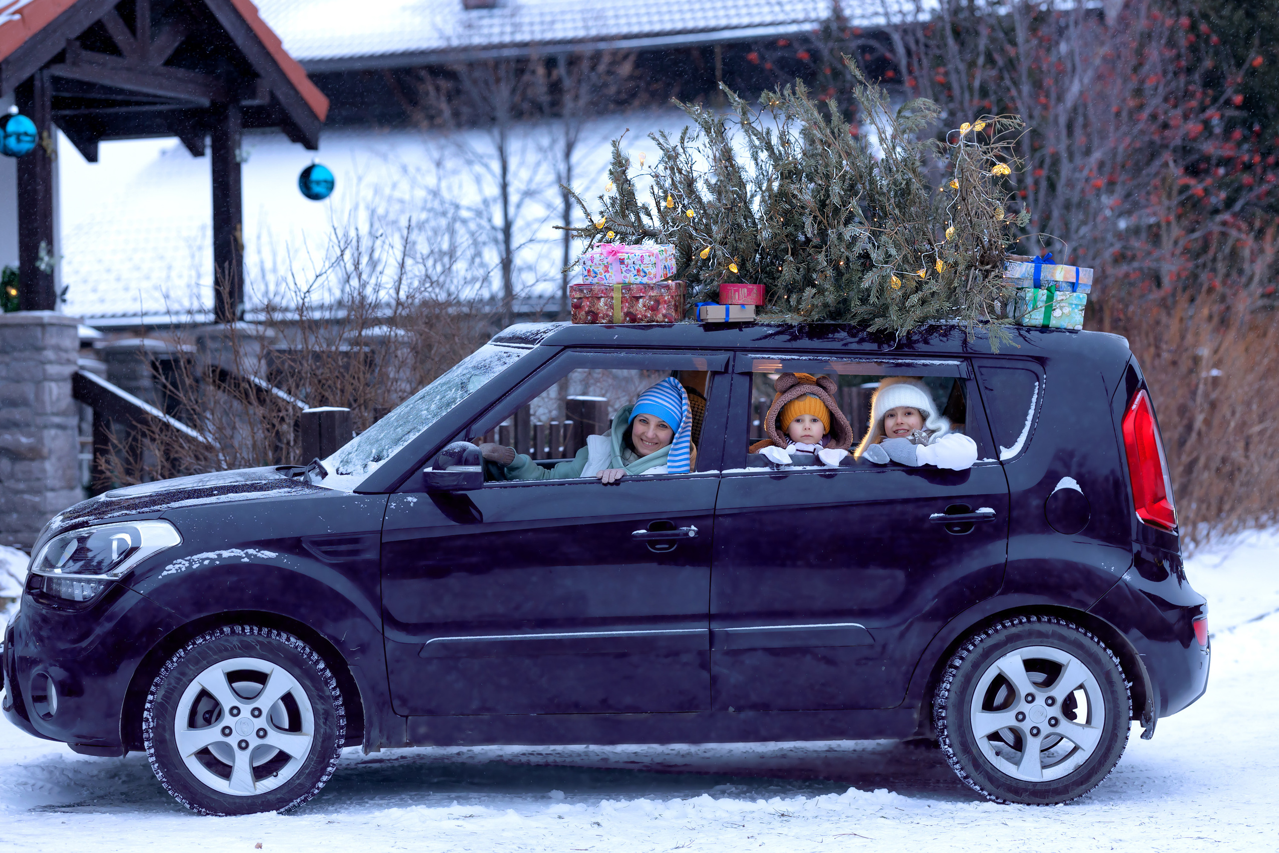 Новогодняя машина с ёлкой на крыше. Счастливая семья в машине