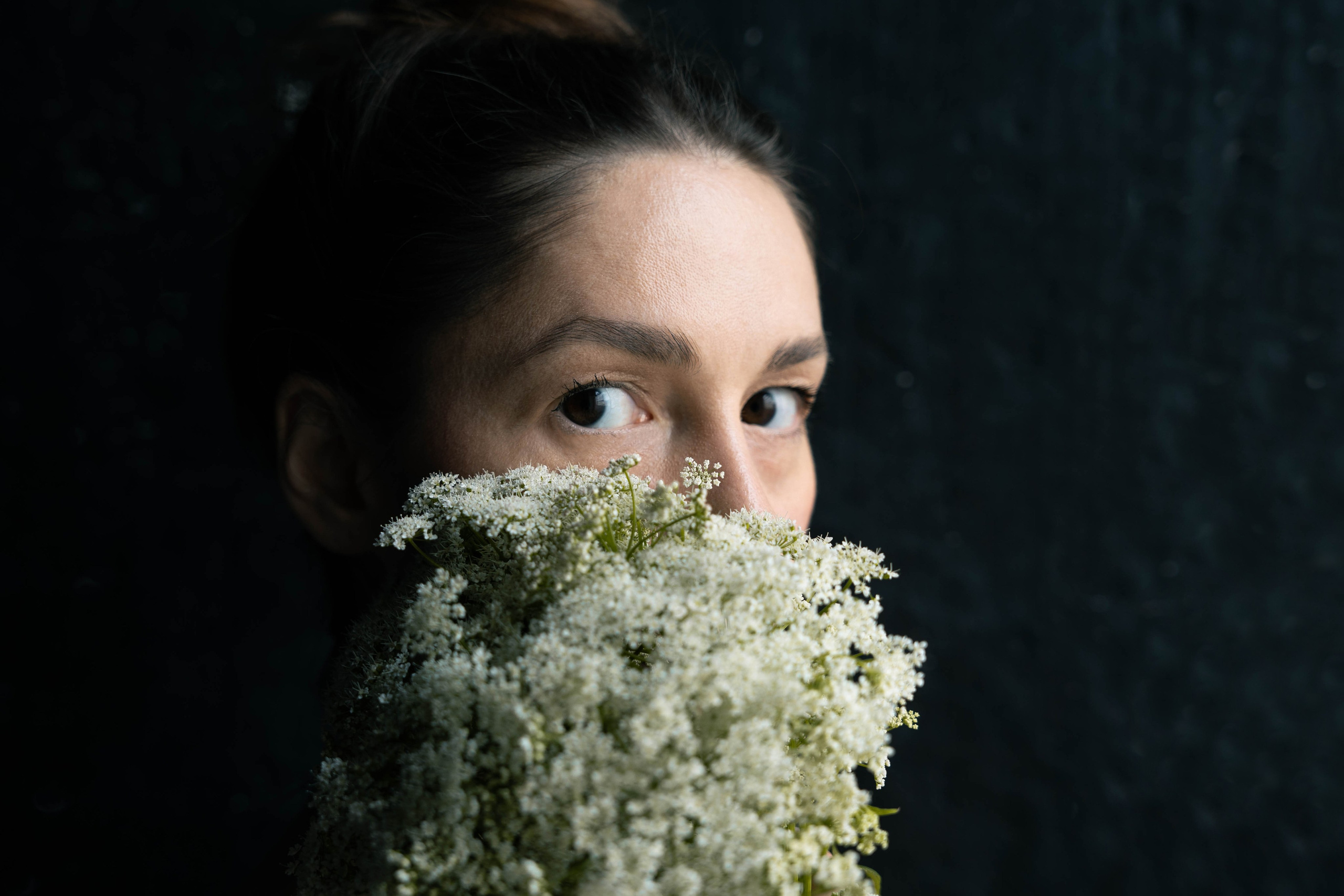 крупный план девушка с темными волосами смотрит черех букет цветов 