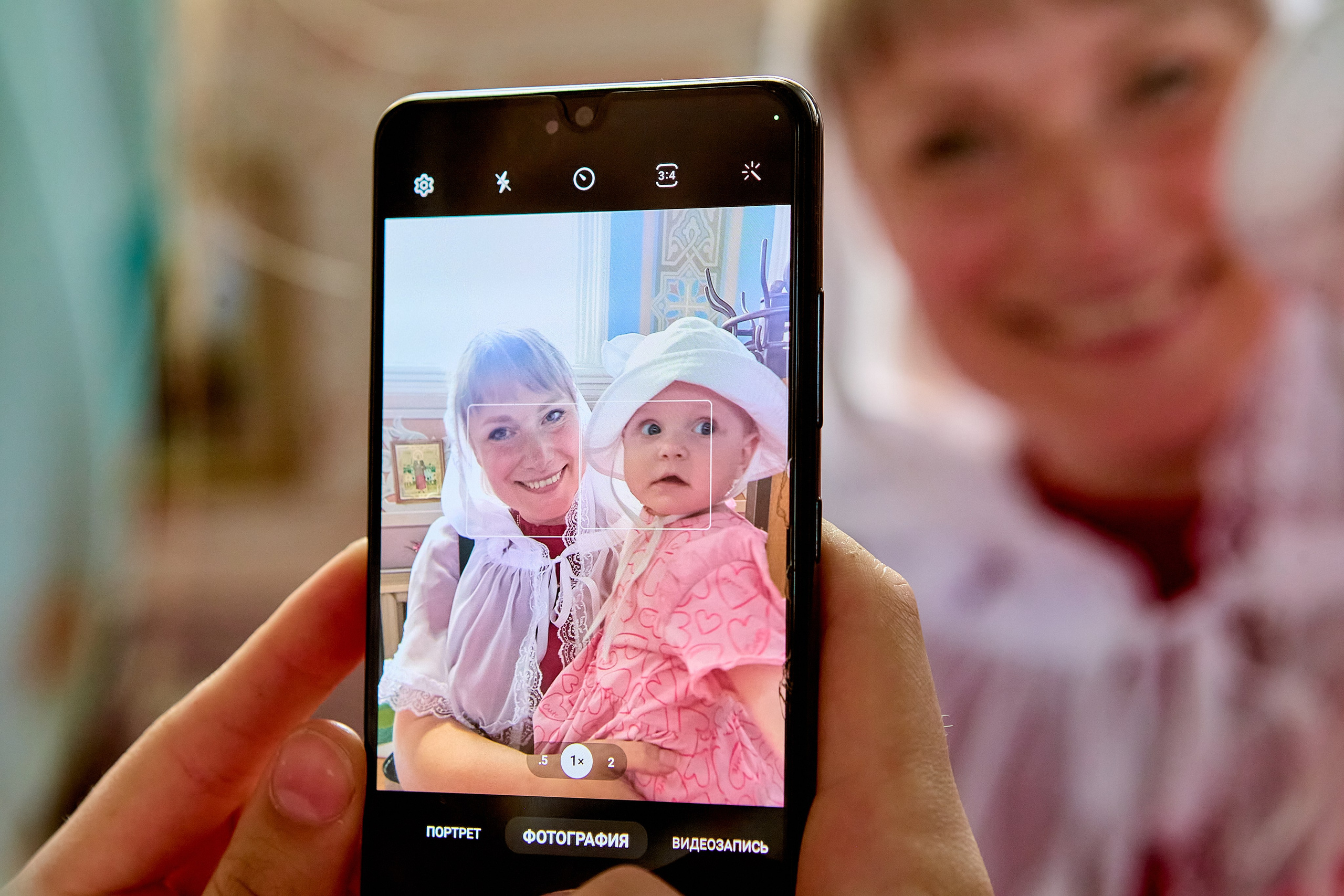 Портрет девочки одного годика через телефон На телефон фотографируют девочку одного годика перед крещением