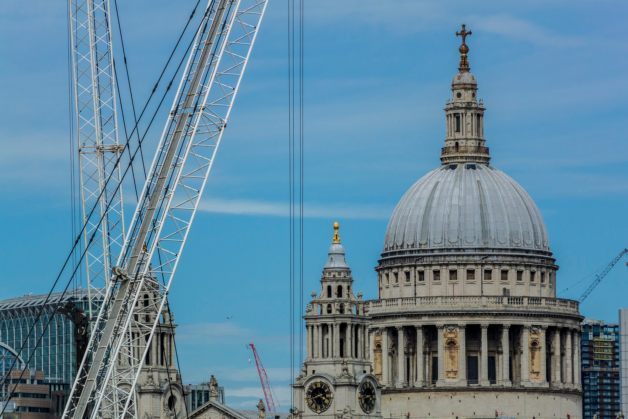 Исторический купол собора Святого Павла в Лондоне на фоне современного строительного крана, чистое голубое небо, резкие линии.