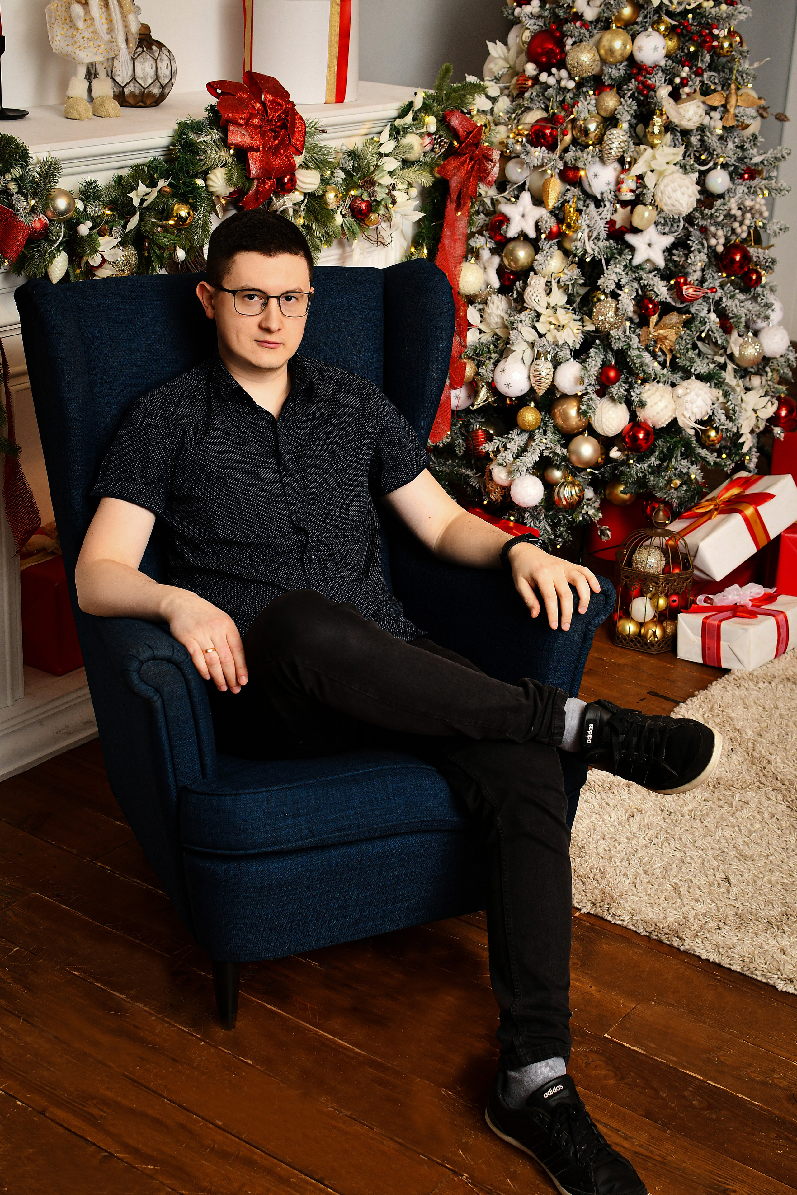 Мужчина сидит в кресле в студии с новогодним декором