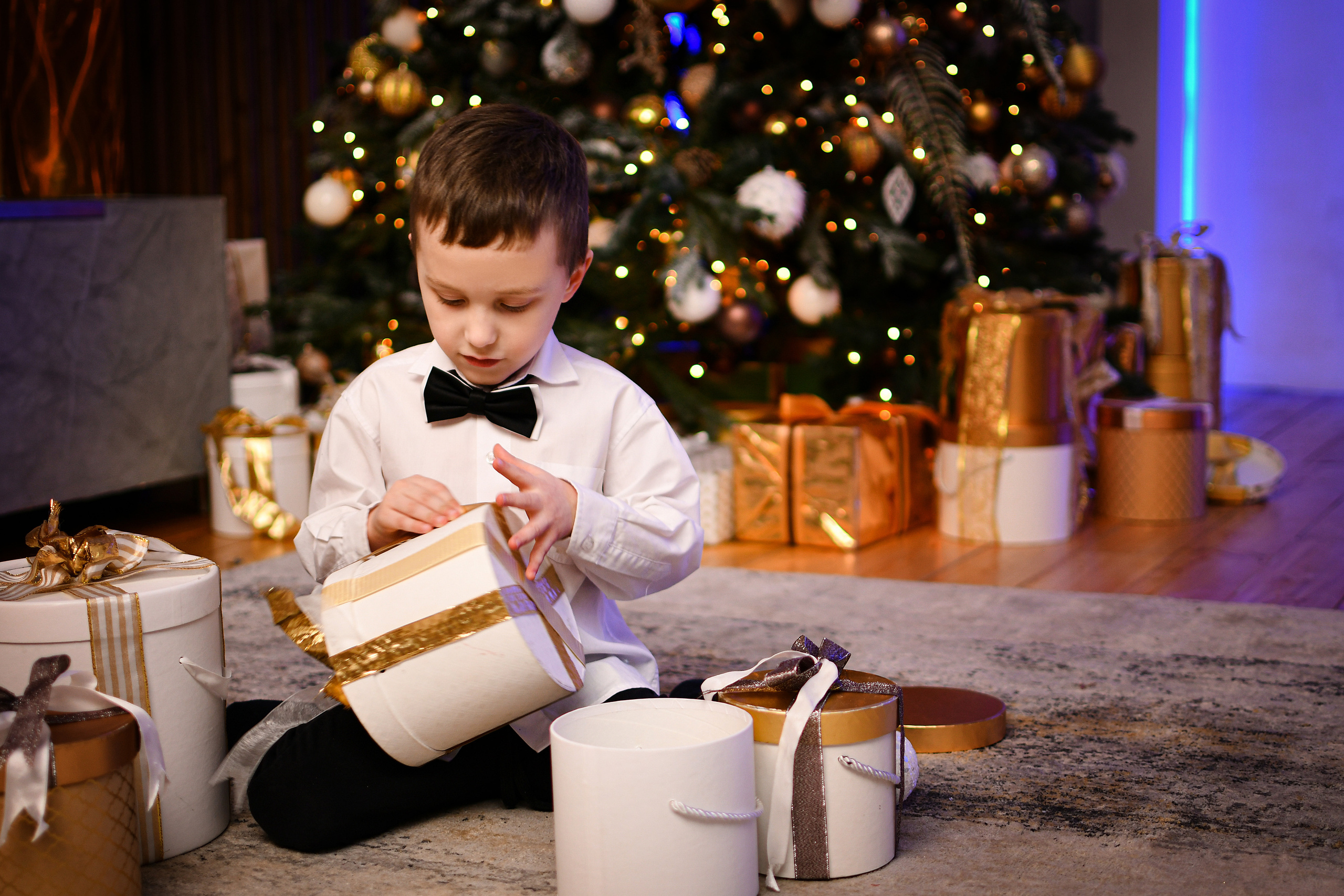 Мальчик открывает подарки на фоне новогодней ёлки