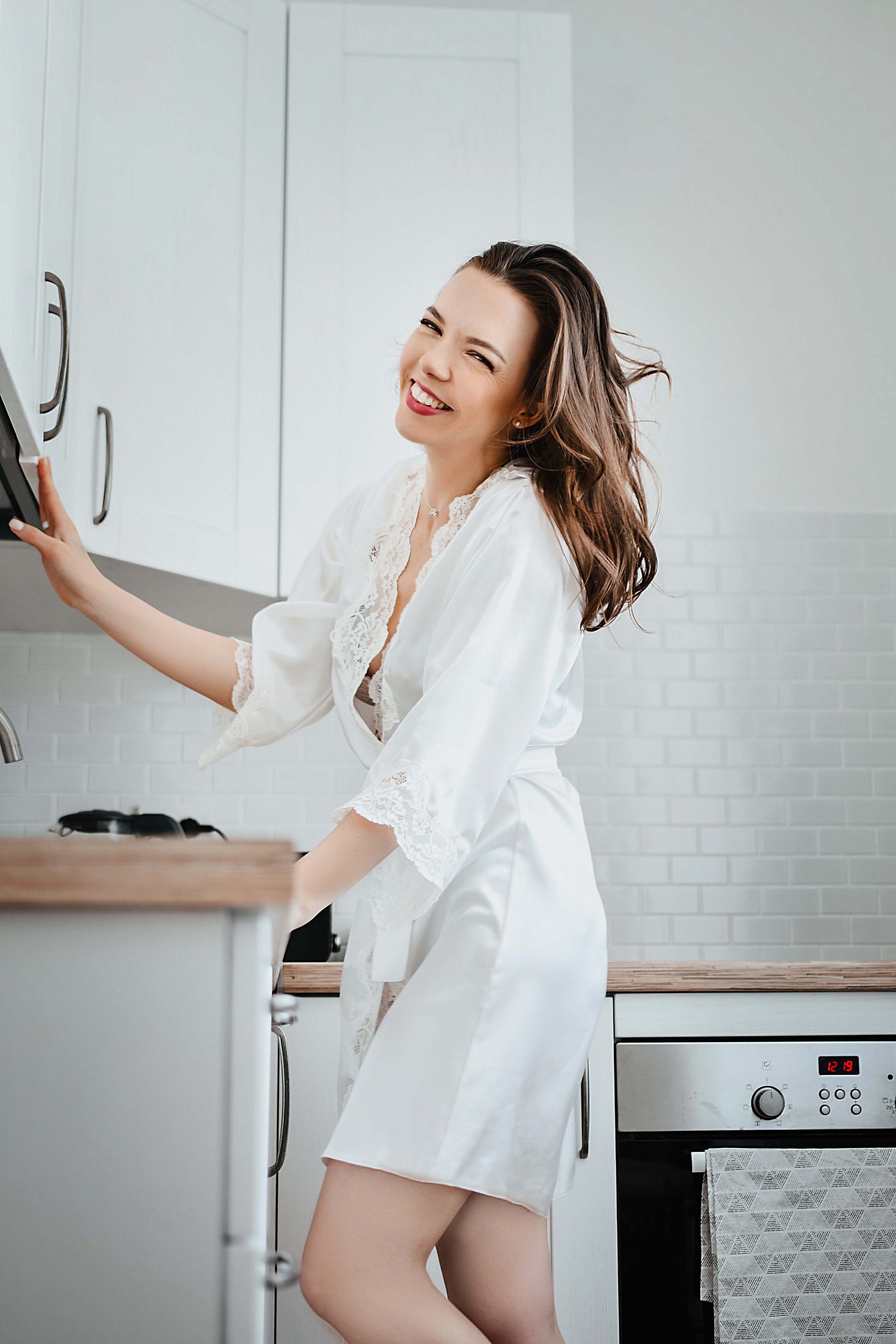 Девушка стоит на своей кухне и смеется