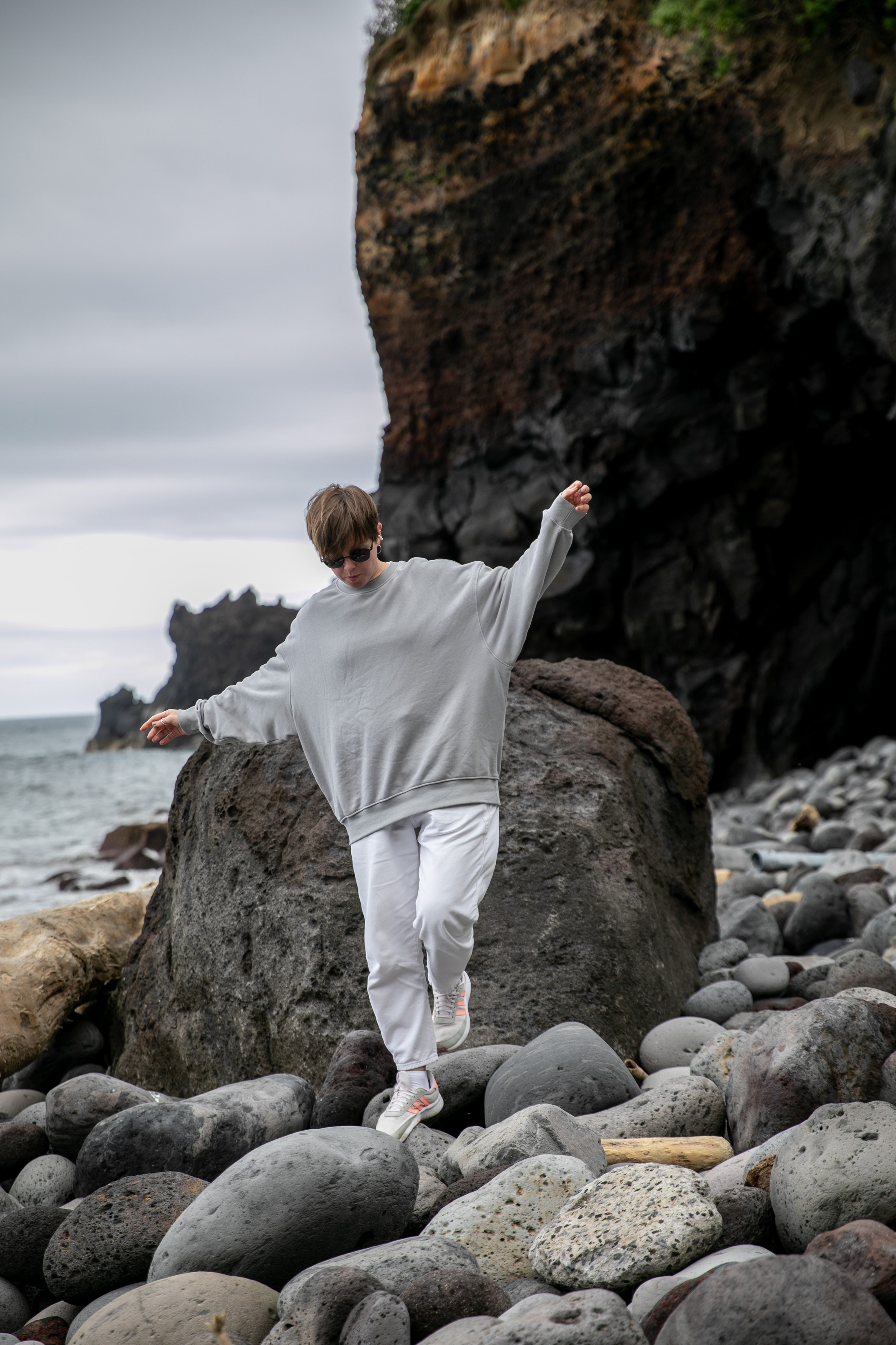 Young women exploring the breathtaking scenery of the Azores, with rolling hills, the ocean, and sky as their backdrop