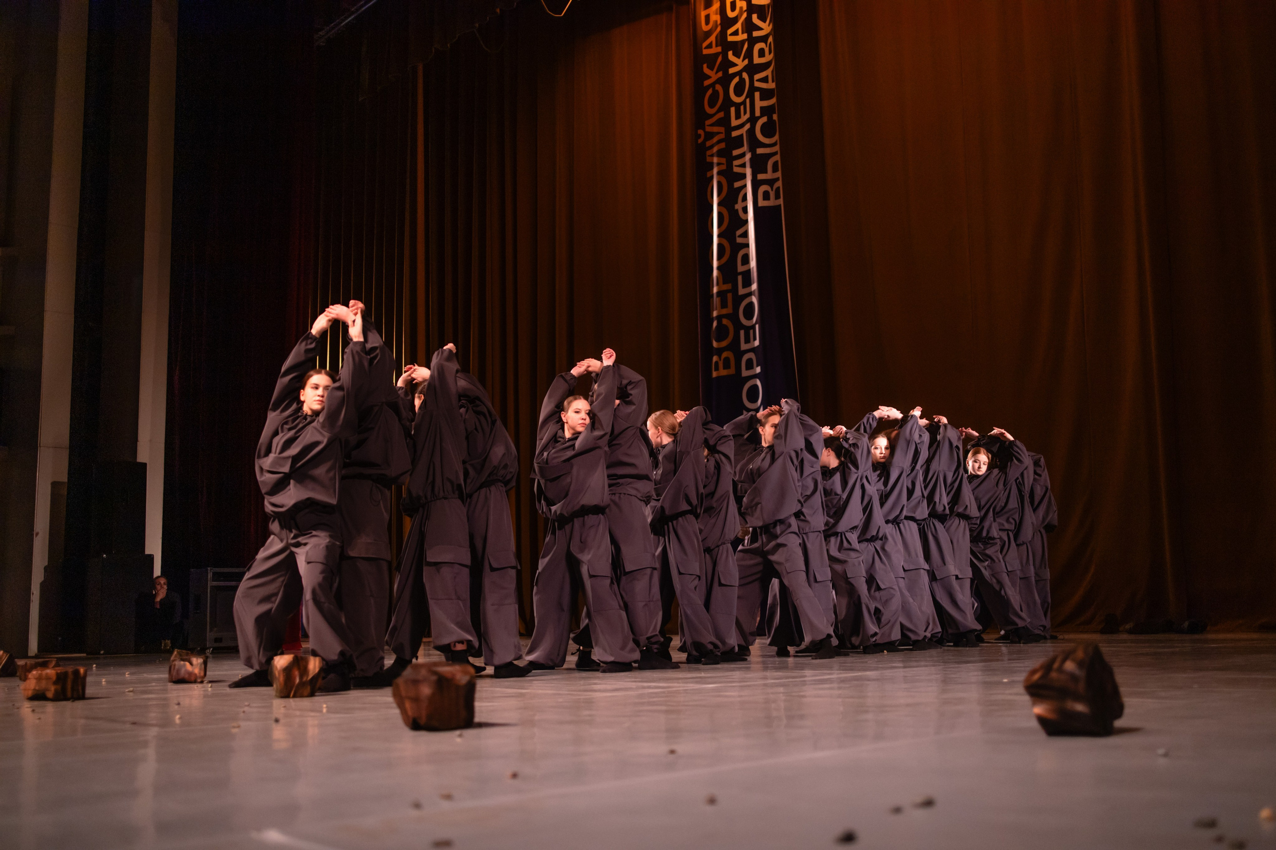 Общий план выступления с хореографическим реквизитом (каски, камни) на сцене.