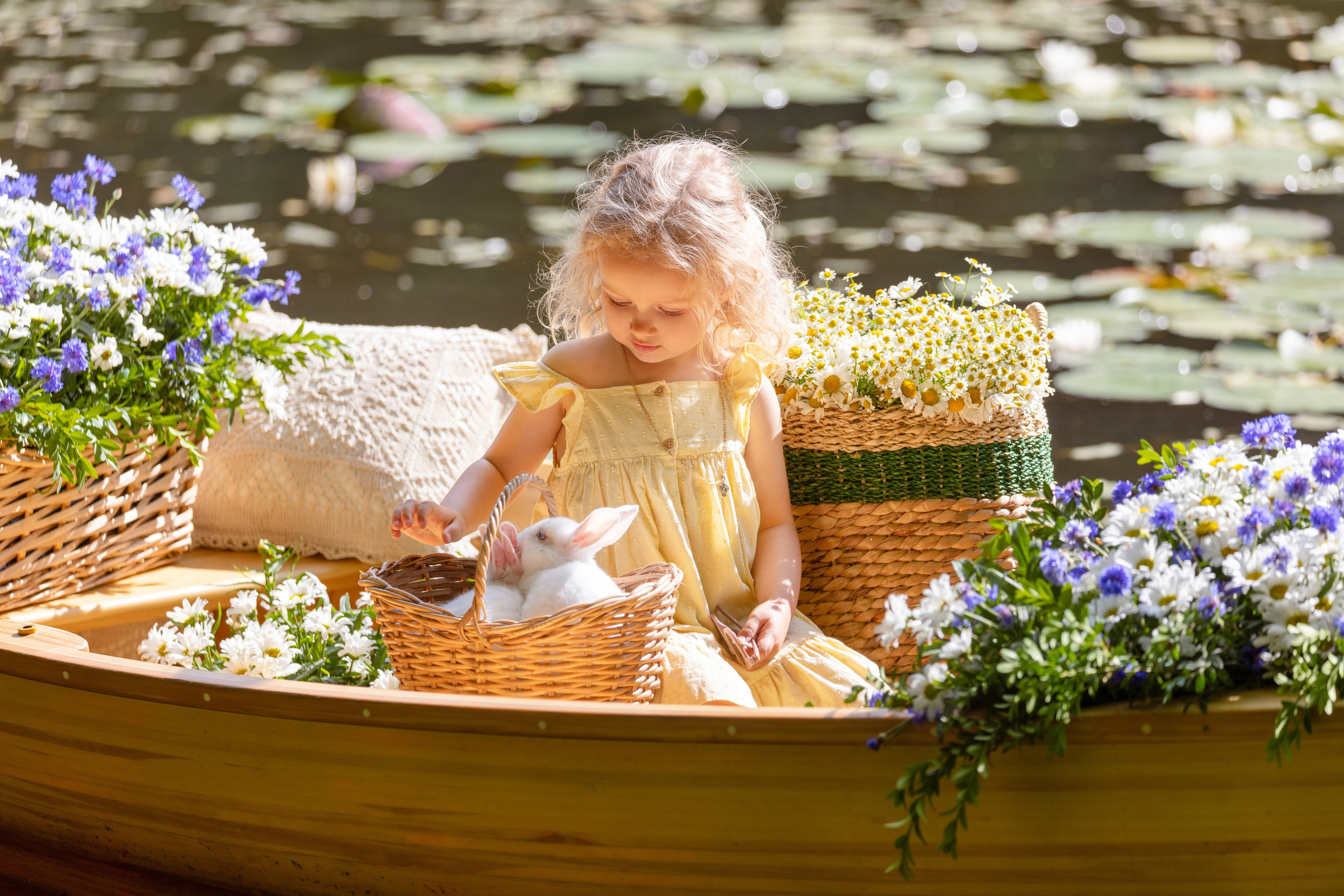 Девочка в пруду на лодке гладит кроликов  сидящих в корзине