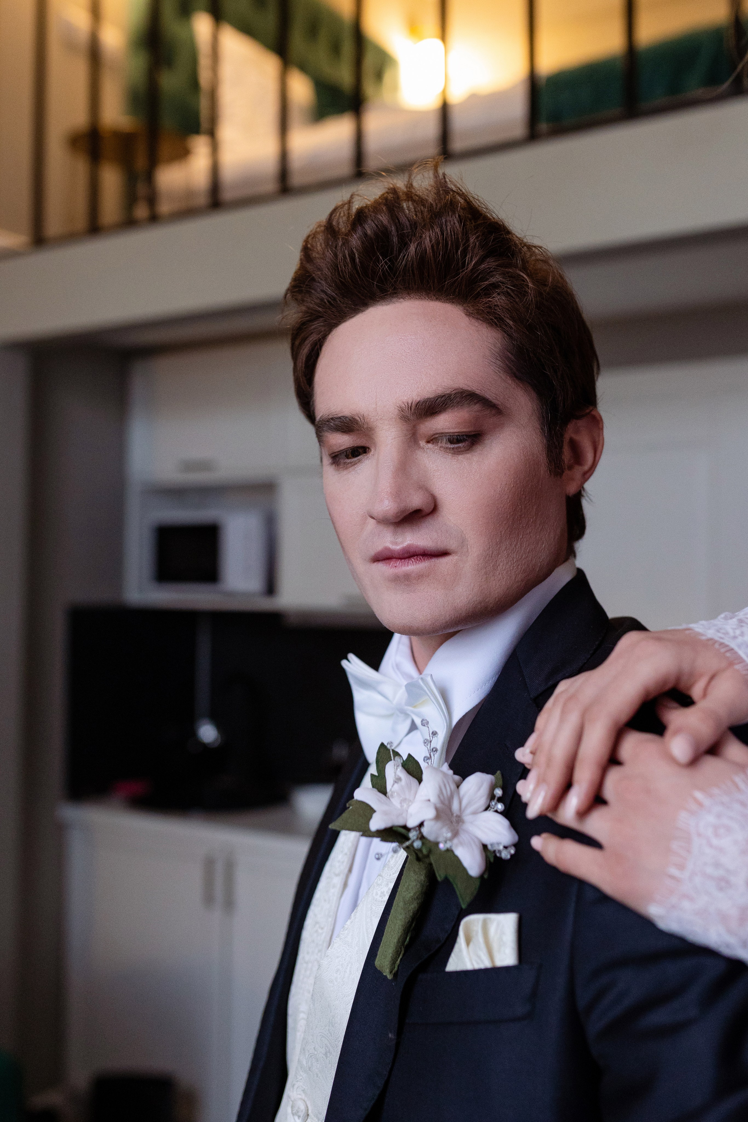 Жених смотрит на руки невесты, которые лежат на его плече.